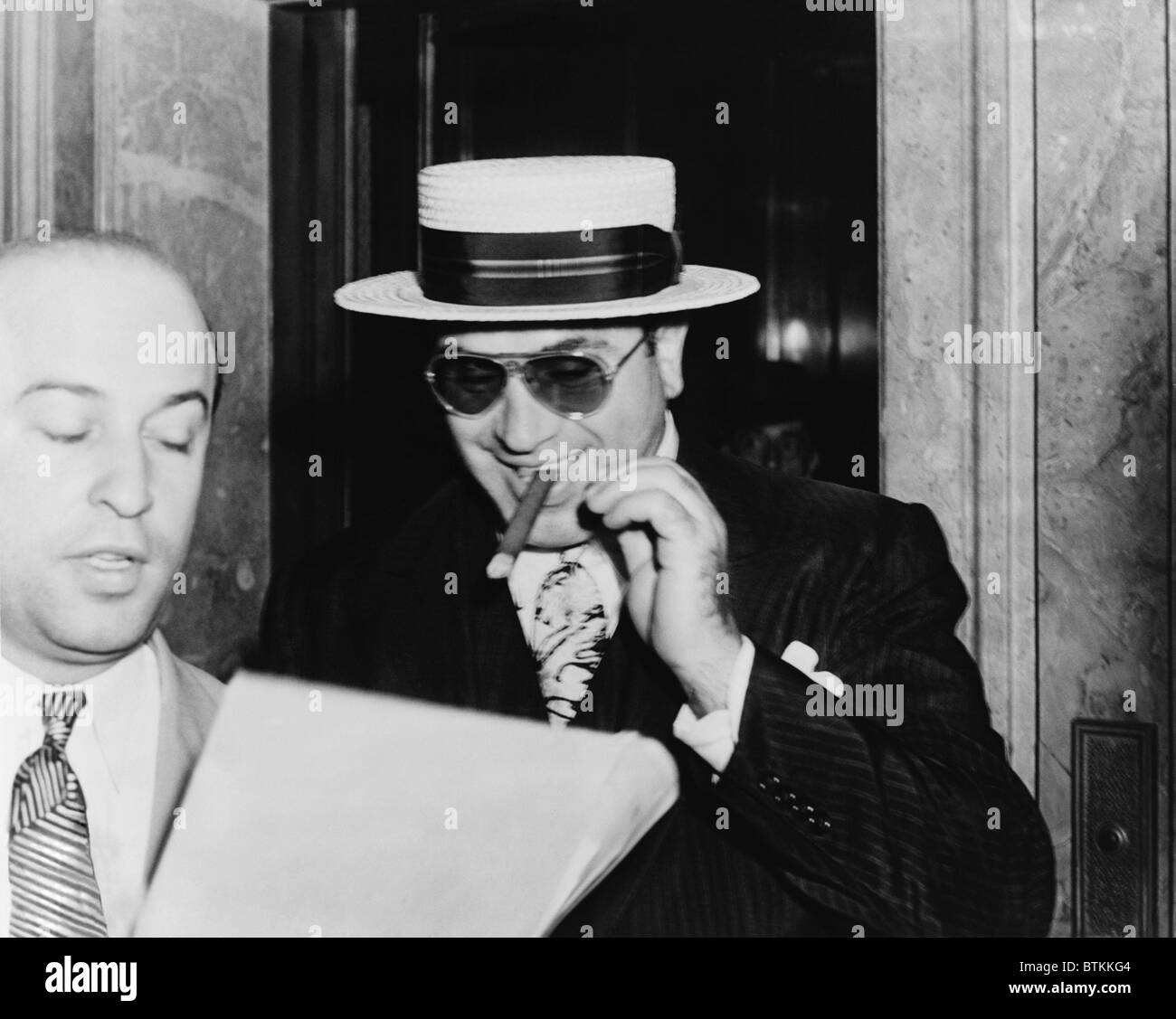 Al Capone, avec un cigare et un grand sourire, laissant un édifice fédéral à Miami, Floride, précédé par son procureur Abe Teitelbaum. 1941. Banque D'Images