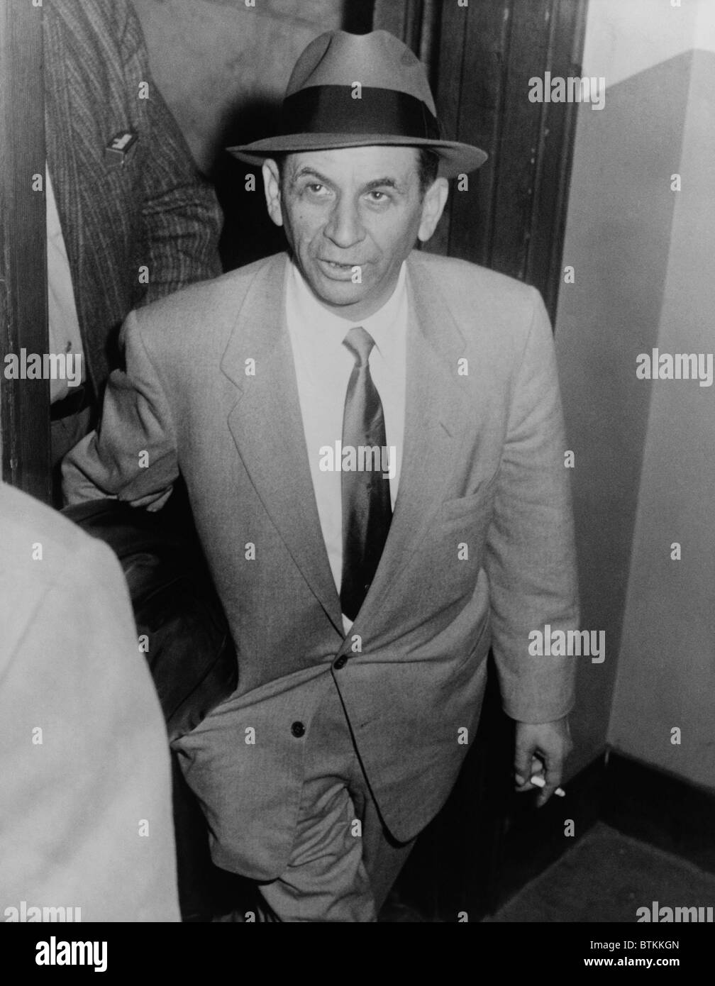 Boss jeu Meyer Lansky (1902-1983), dirigé par un détective pour la réservation sur le vagabondage à 54th Street station de police, la ville de New York, le 13 février 1958. Banque D'Images