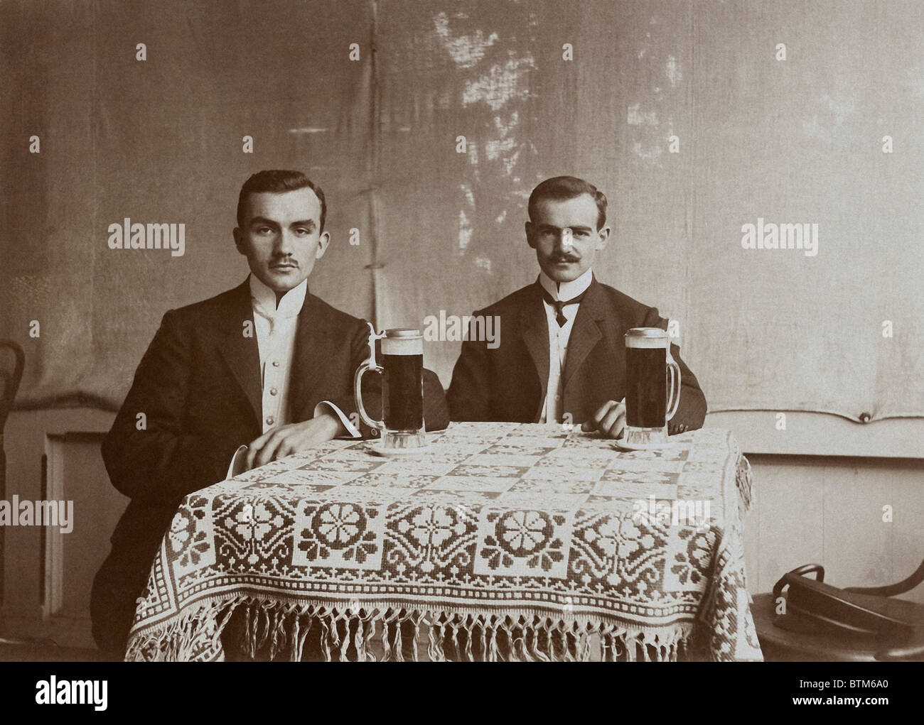 Photo historique (1910) de deux hommes en train de boire une bière Banque D'Images