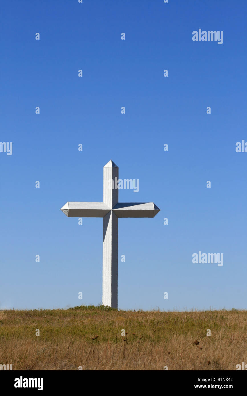 Croix blanche géante s'élevant de la prairie avec fond de ciel bleu et copy space Banque D'Images