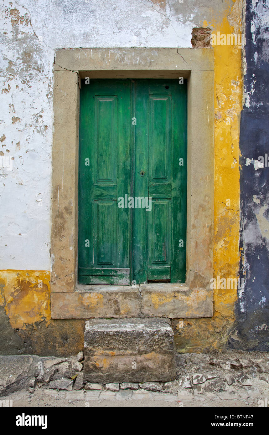 Porte en bois vert avec pierre sculpté à la main contre un mur texturé dans le village médiéval d'Obidos Banque D'Images