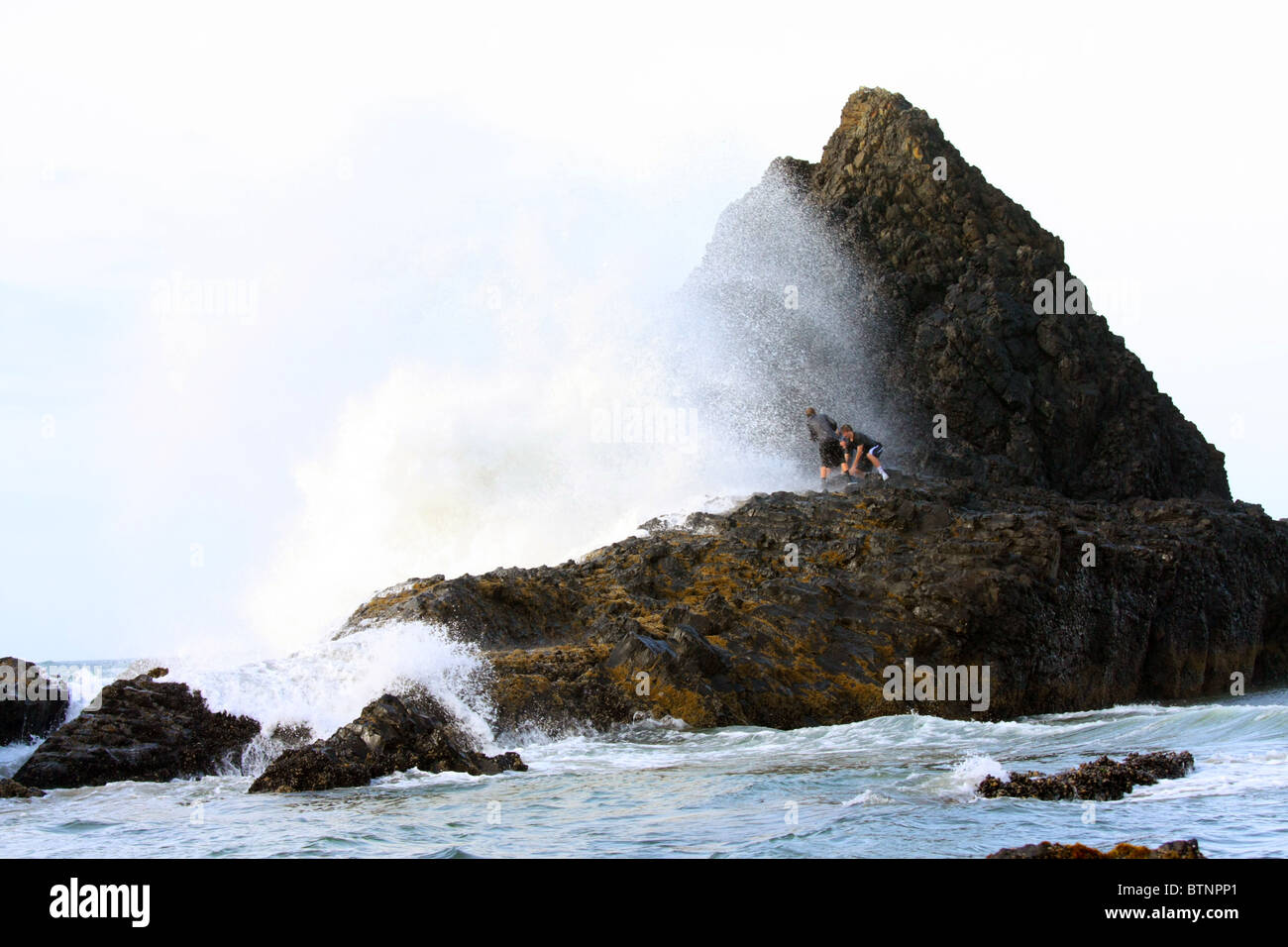 Trois jeunes garçons défiant les décès et les blessures qu'ils se moquent de la colère du surf et les grandes vagues de l'océan. Banque D'Images