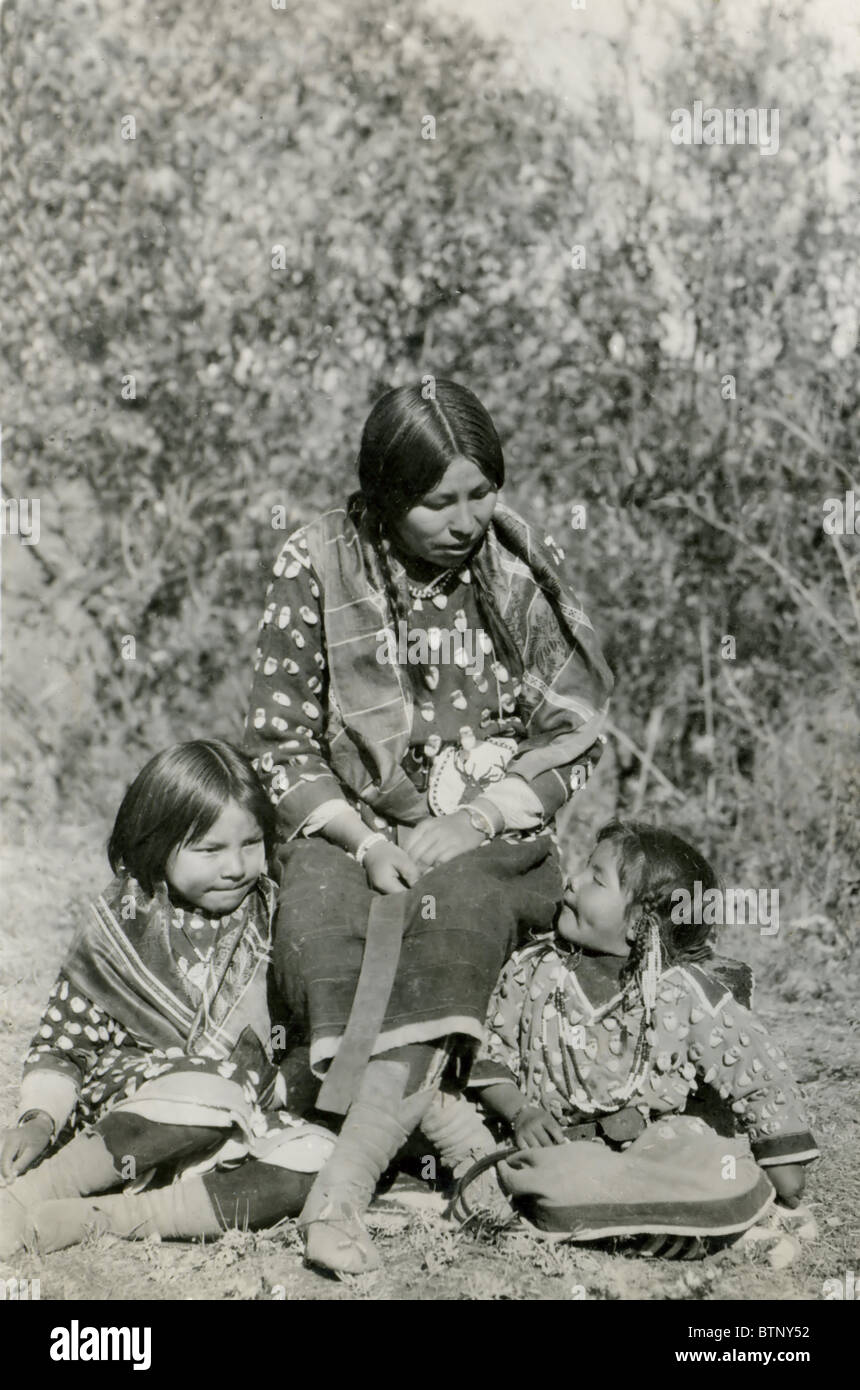Une photo montrant un Native American Indian mère dire à ses deux filles histoire vêtus de vêtements autochtones. Cette photo est en noir et blanc. Banque D'Images
