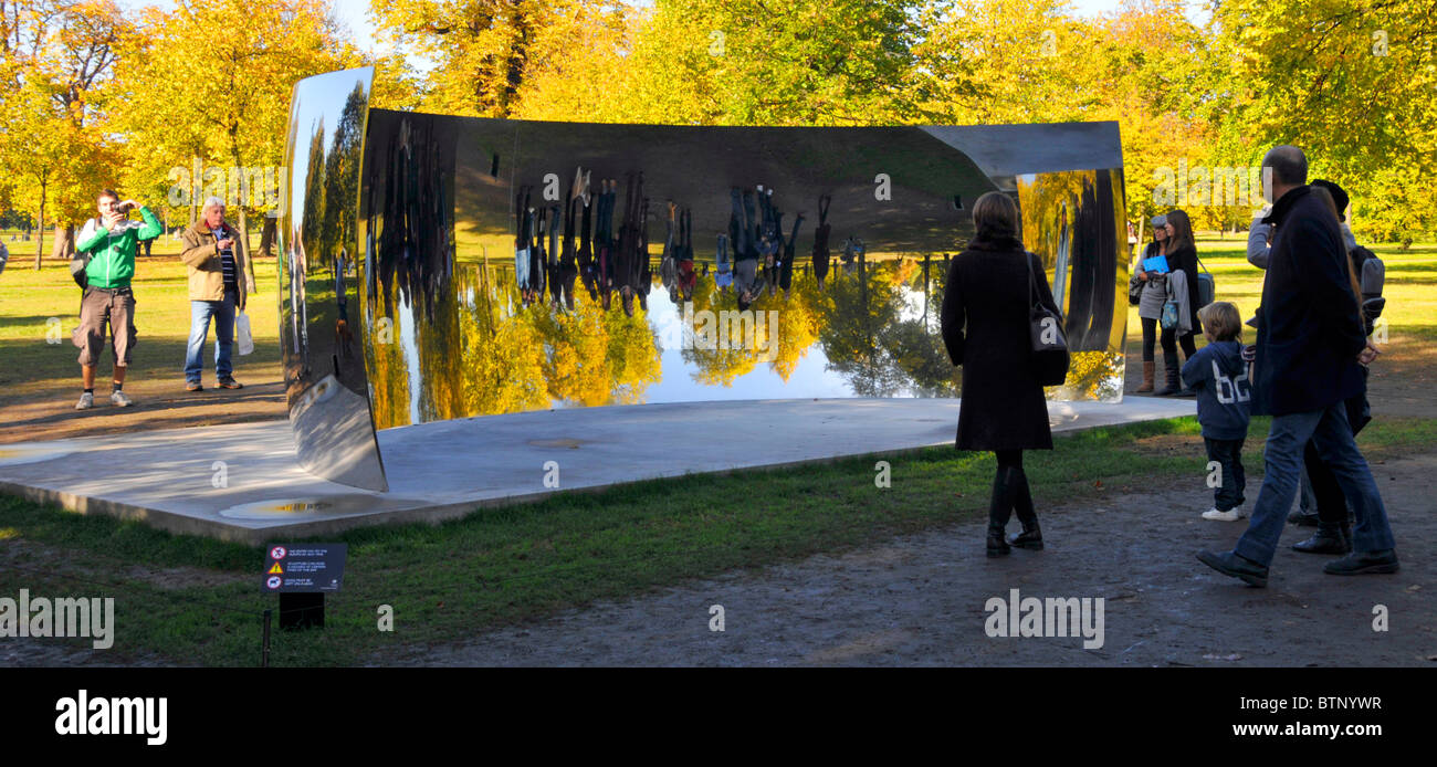 Touristes à Kensington Gardens regardant des images reflétées d'eux-mêmes dans l'un des Anish Kapoor Sky Mirrors C Curve Londres Angleterre Royaume-Uni Banque D'Images