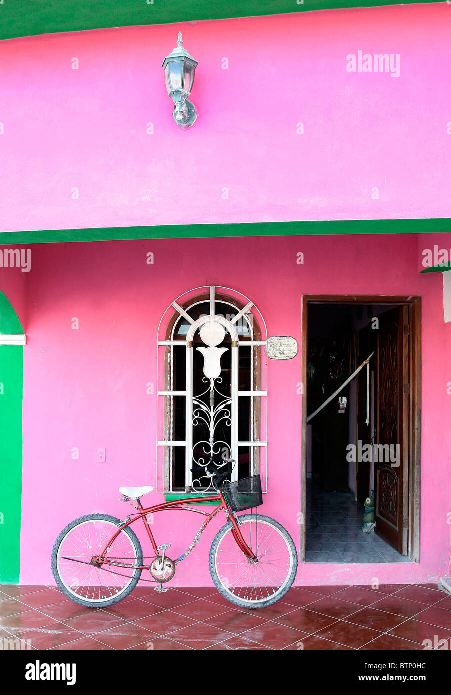 Location rouge très coloré s'appuyant sur une maison rose et vert sur Isla Holbox, état de Quintana Roo, Mexique Banque D'Images