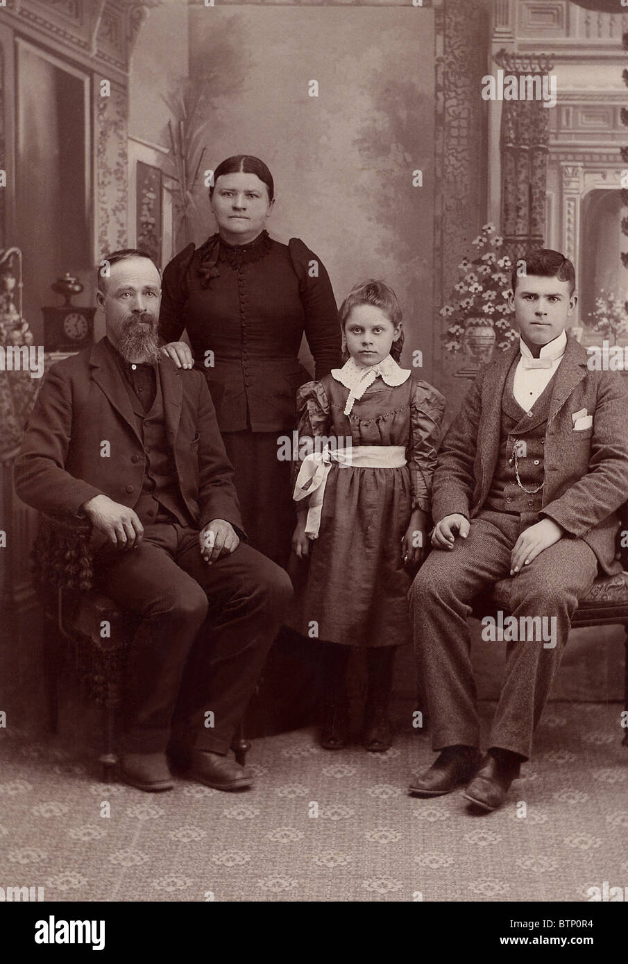 1890 vintage photo famille dans un studio shot.Cette photographie est jauni avec l'âge. Assis est le père et le fils avec la mère et la fille debout Banque D'Images