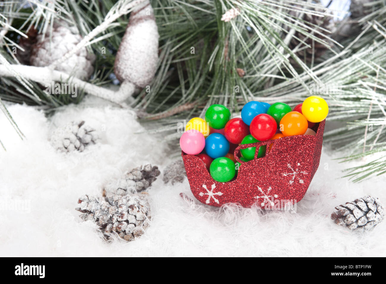 Portrait d'un traîneau de Noël rempli de boules de gomme de couleur situé dans un arbre de pin, de neige fond. Banque D'Images