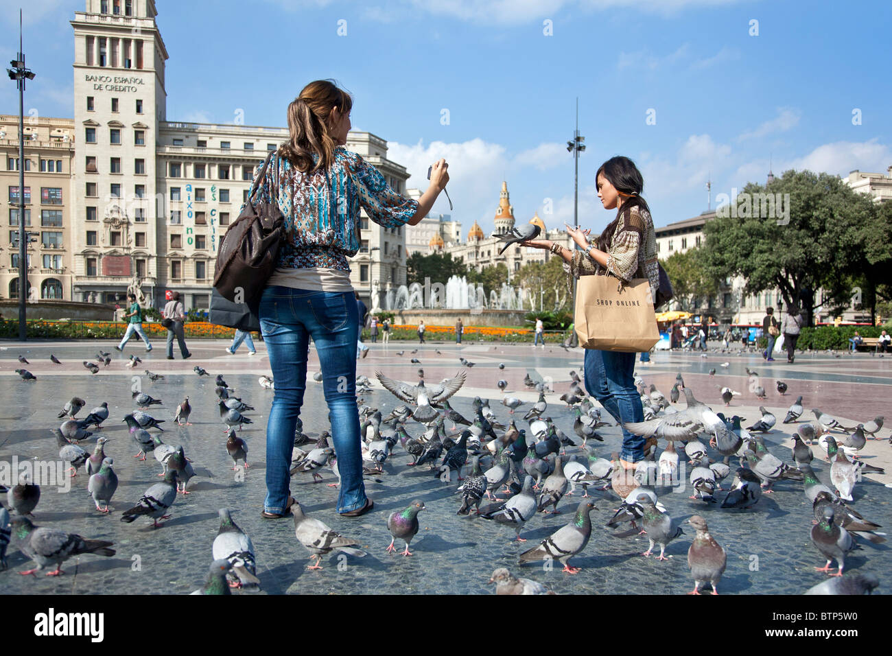 Les jeunes femmes se nourrir les pigeons. La place Catalunya. Barcelone. Espagne Banque D'Images