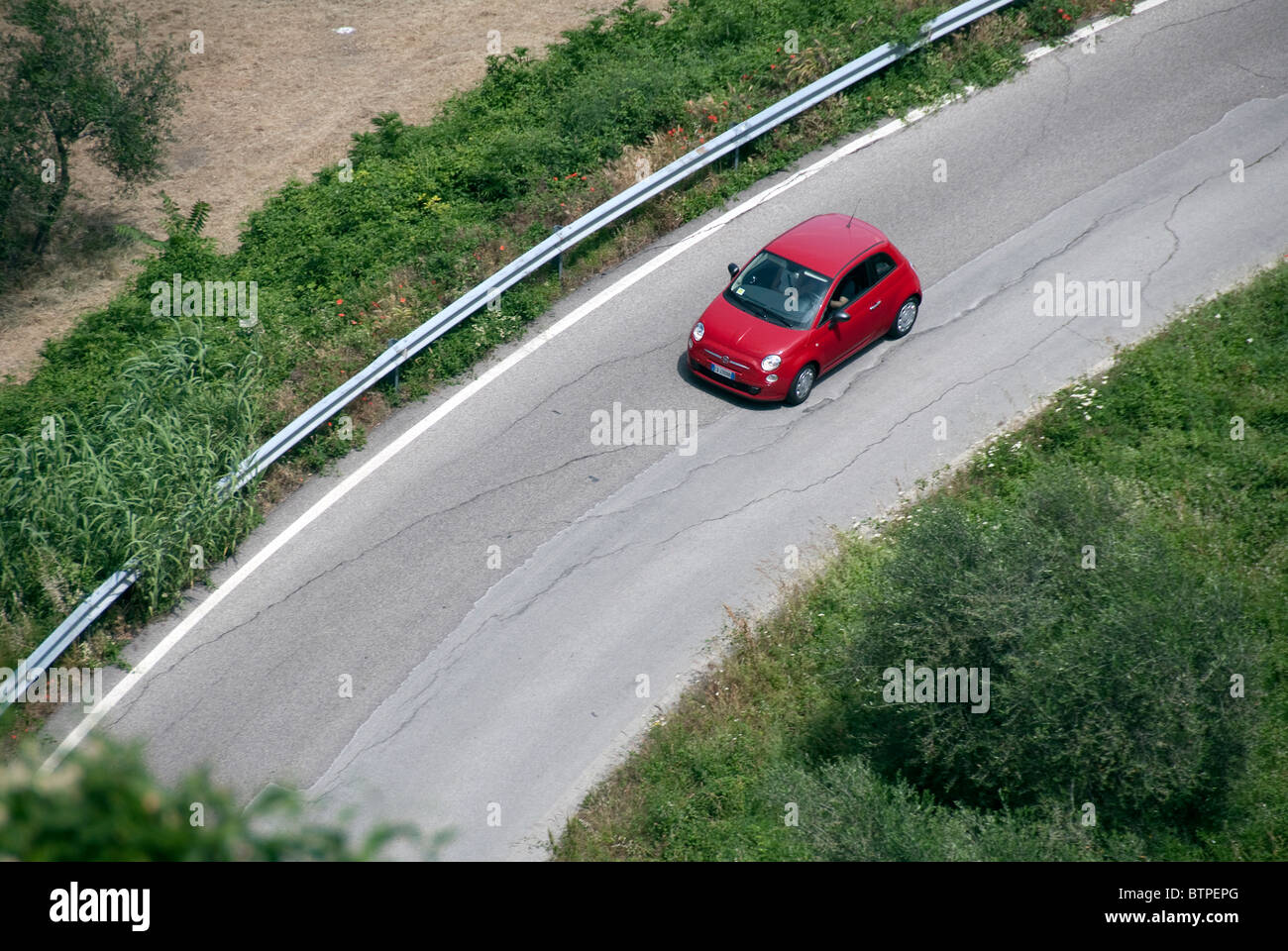 Petit rouge Fiat 500 (Modèle 2008) a lancé la vision d'en haut sur une route en Italie mais pourrait être n'importe où. Le bras de l'homme et de la femme visible Banque D'Images