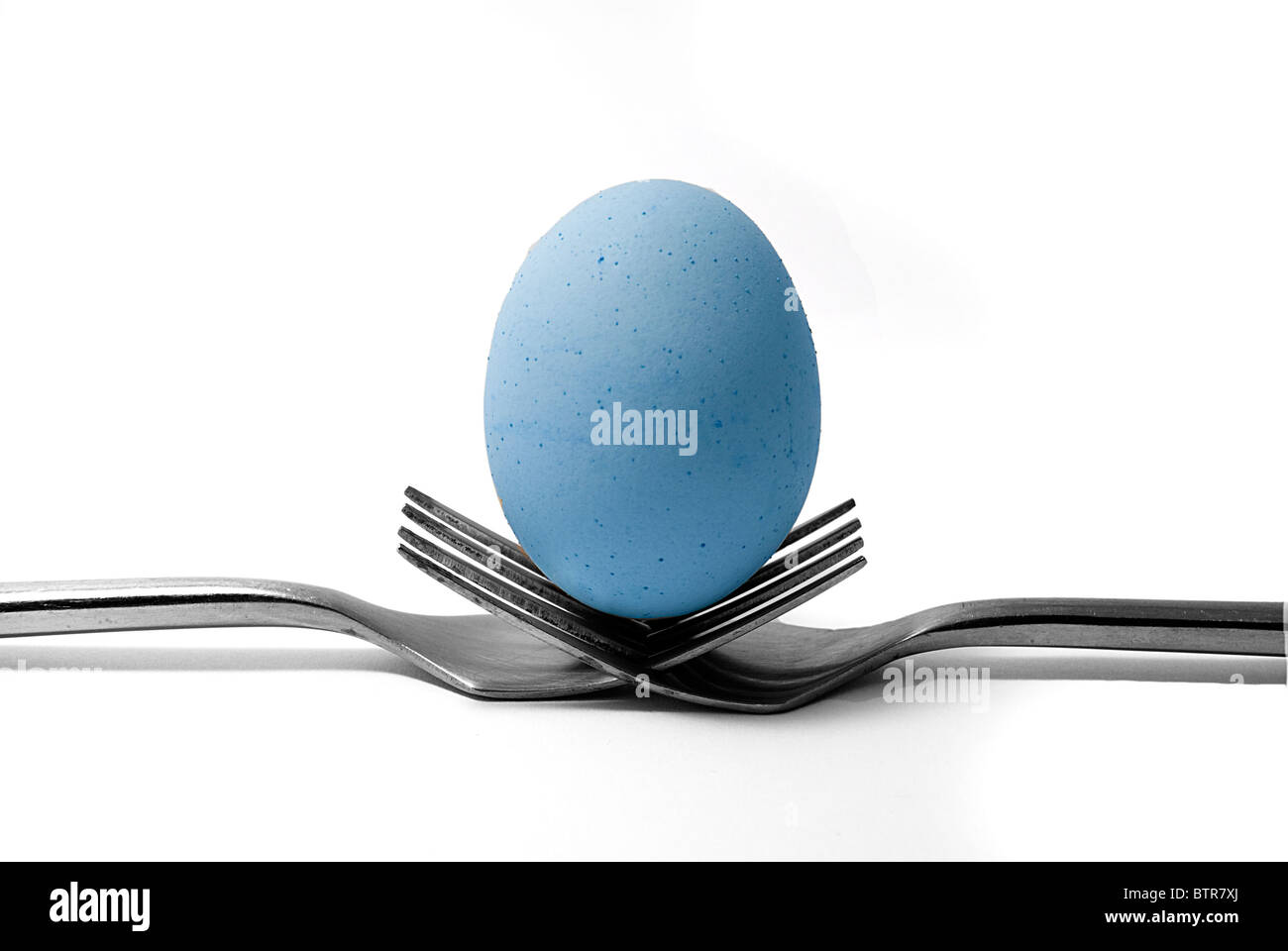 Fine art image d'un oeuf bleu en équilibre sur deux fourchettes. Banque D'Images