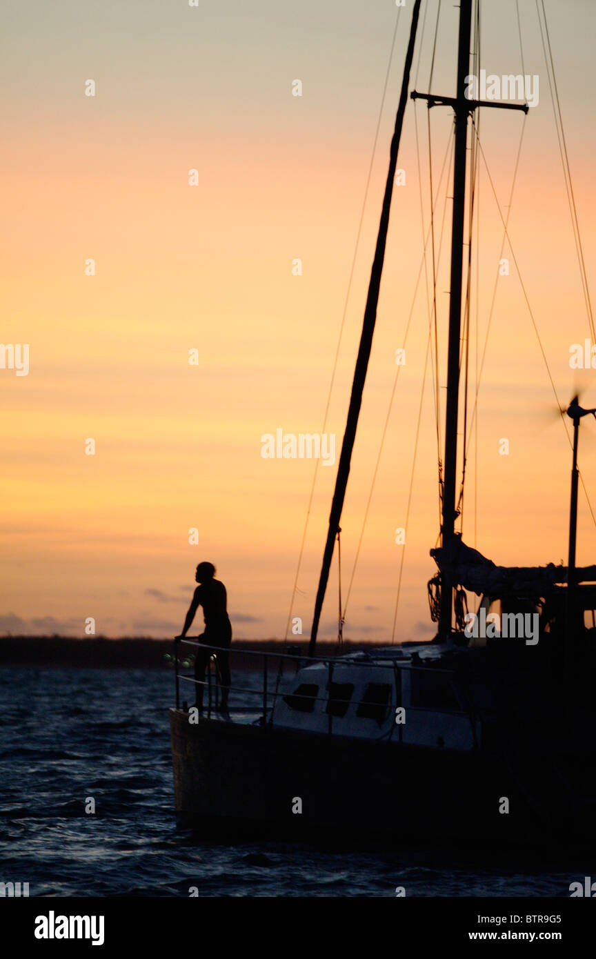 L'Australie, Darwin, Silhouette d'homme debout sur le voilier au coucher du soleil Banque D'Images