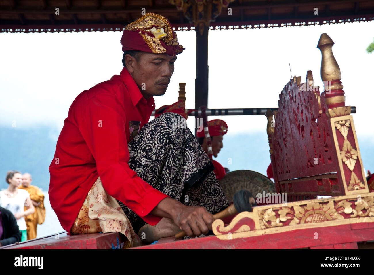 Le gamelan balinais musiciens jouant de leurs instruments à Bali portant un costume traditionnel avec des couleurs rouge vif Banque D'Images