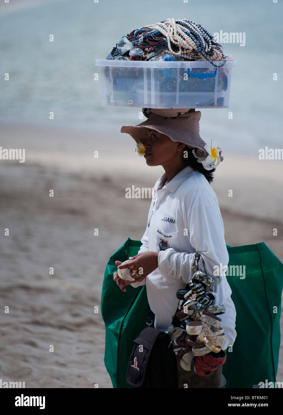 Femme vente de bijoux sur la plage de Nusa Dua Bali Indonésie exerçant son  panier sur la tête Photo Stock - Alamy