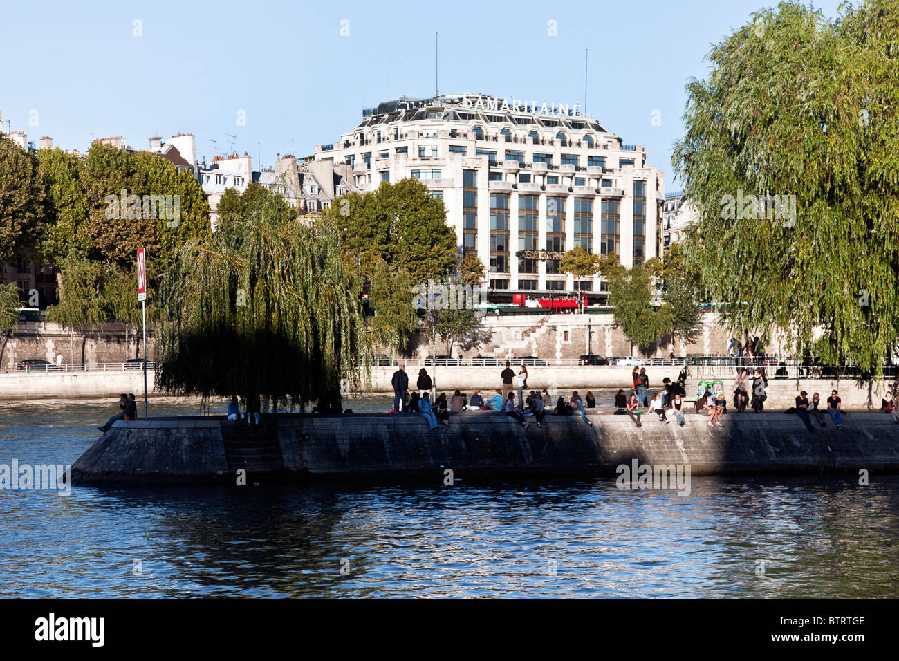 Les eaux bleues de Seine séparer autour de la pointe de l'Ile de la cité où les parisiens le long du bord du quai bénéficiant d'automne chaud soleil Banque D'Images