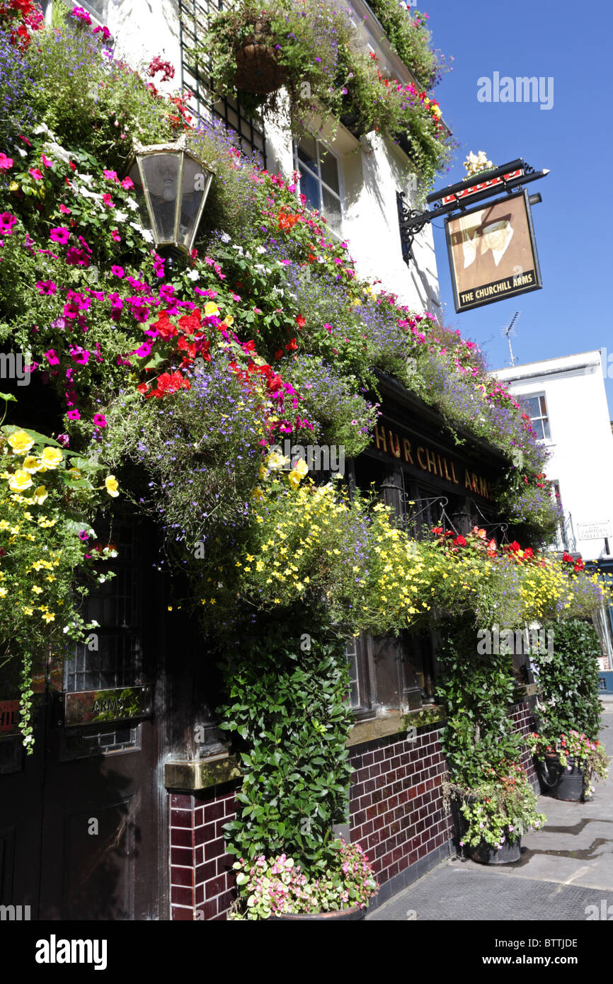 Fleurs merveilleusement organisé affiche ornent la façade extérieure de la Churchill Arms pub populaire à Kensington. Banque D'Images