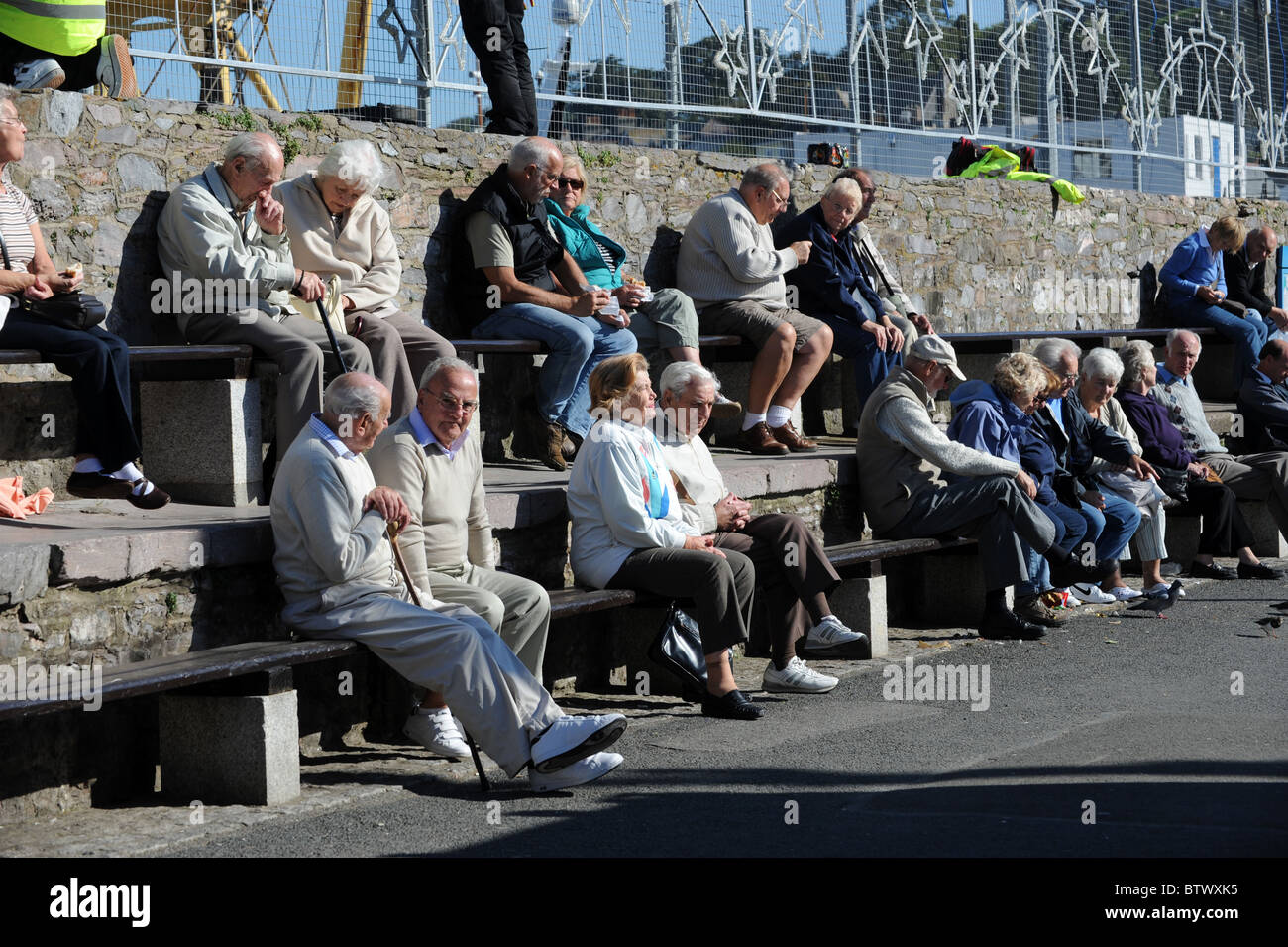 Couples âgés assis au soleil à Brixham à Devon. staycation Britain Banque D'Images