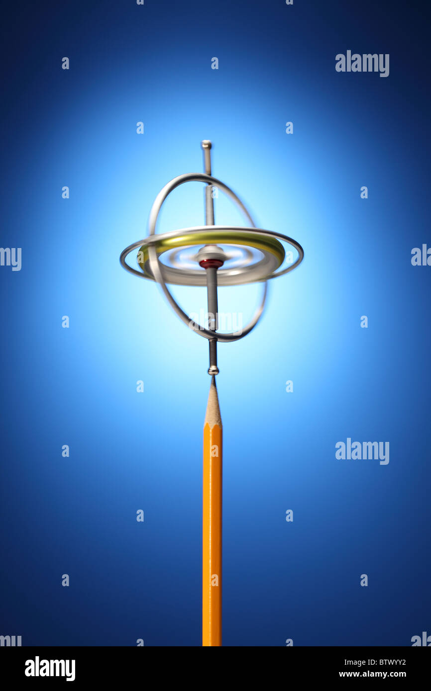Un gyroscope métal en rotation sur la pointe d'un crayon jaune. Banque D'Images