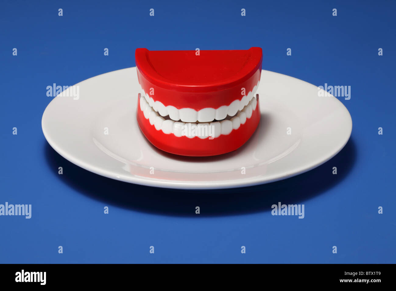 Un jeu de gencives et les dents en plastique sur une assiette blanche Banque D'Images