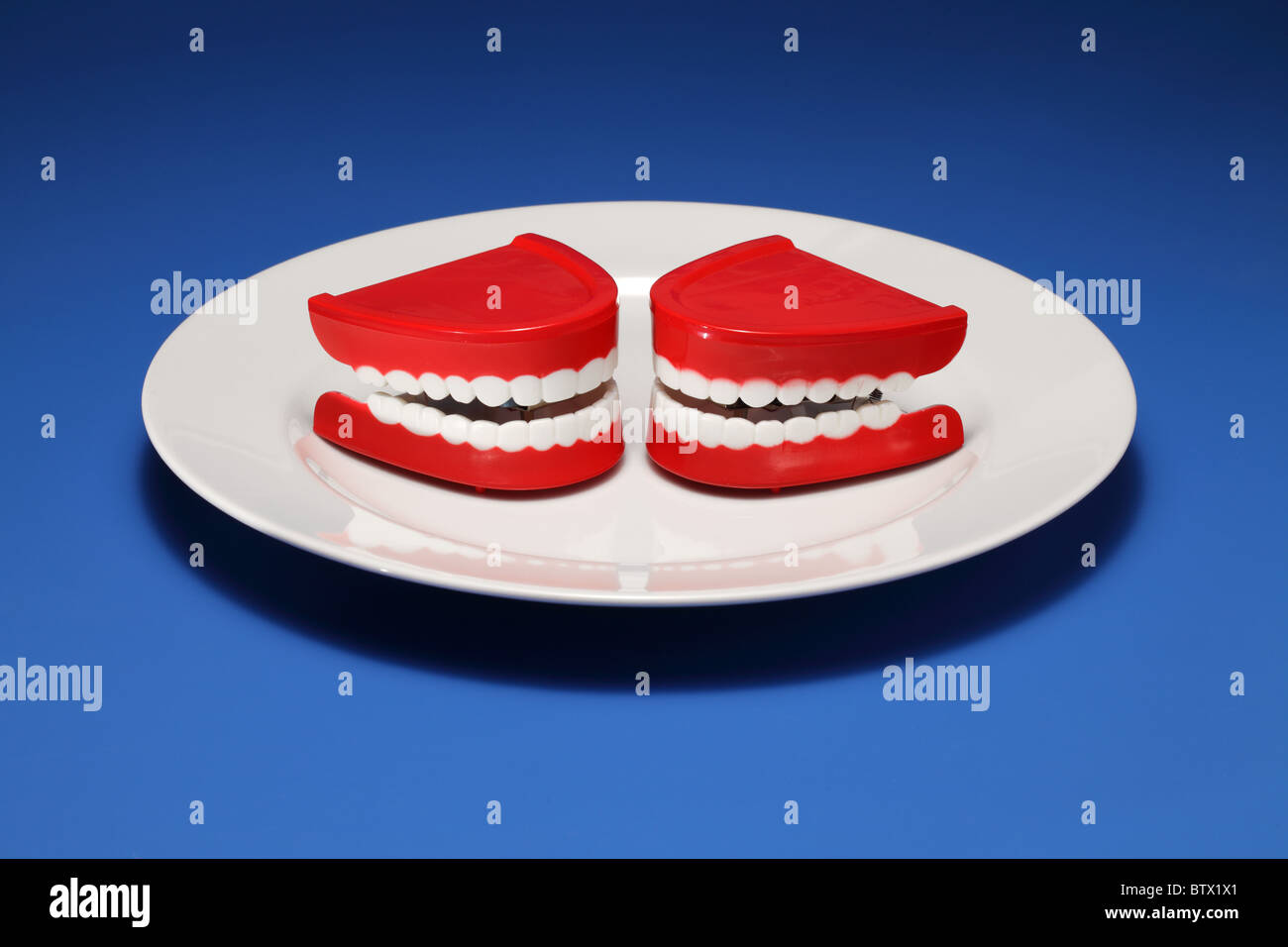 Deux gencives et les dents en plastique sur une assiette blanche Banque D'Images