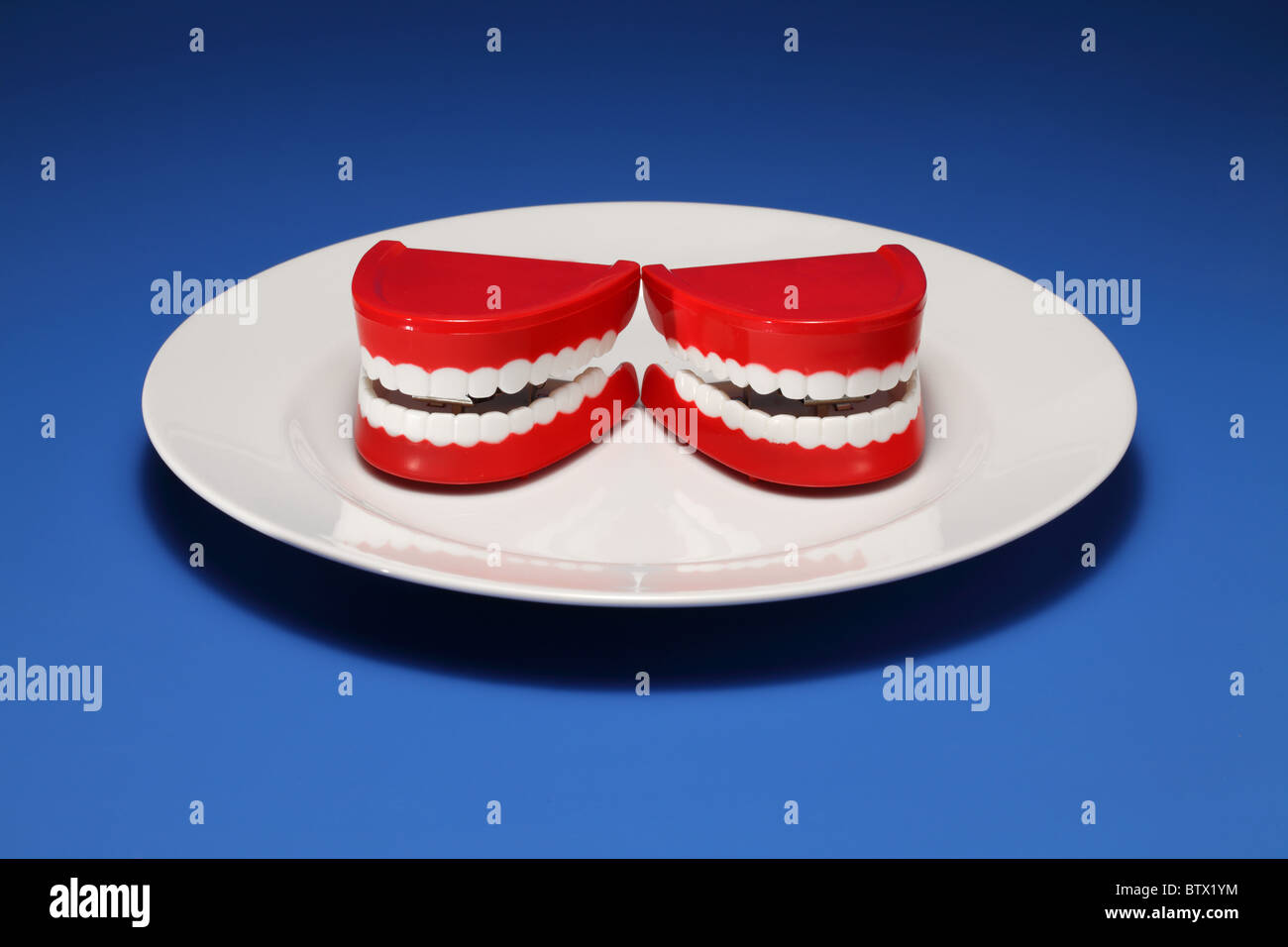 Deux gencives et les dents en plastique sur une assiette blanche Banque D'Images