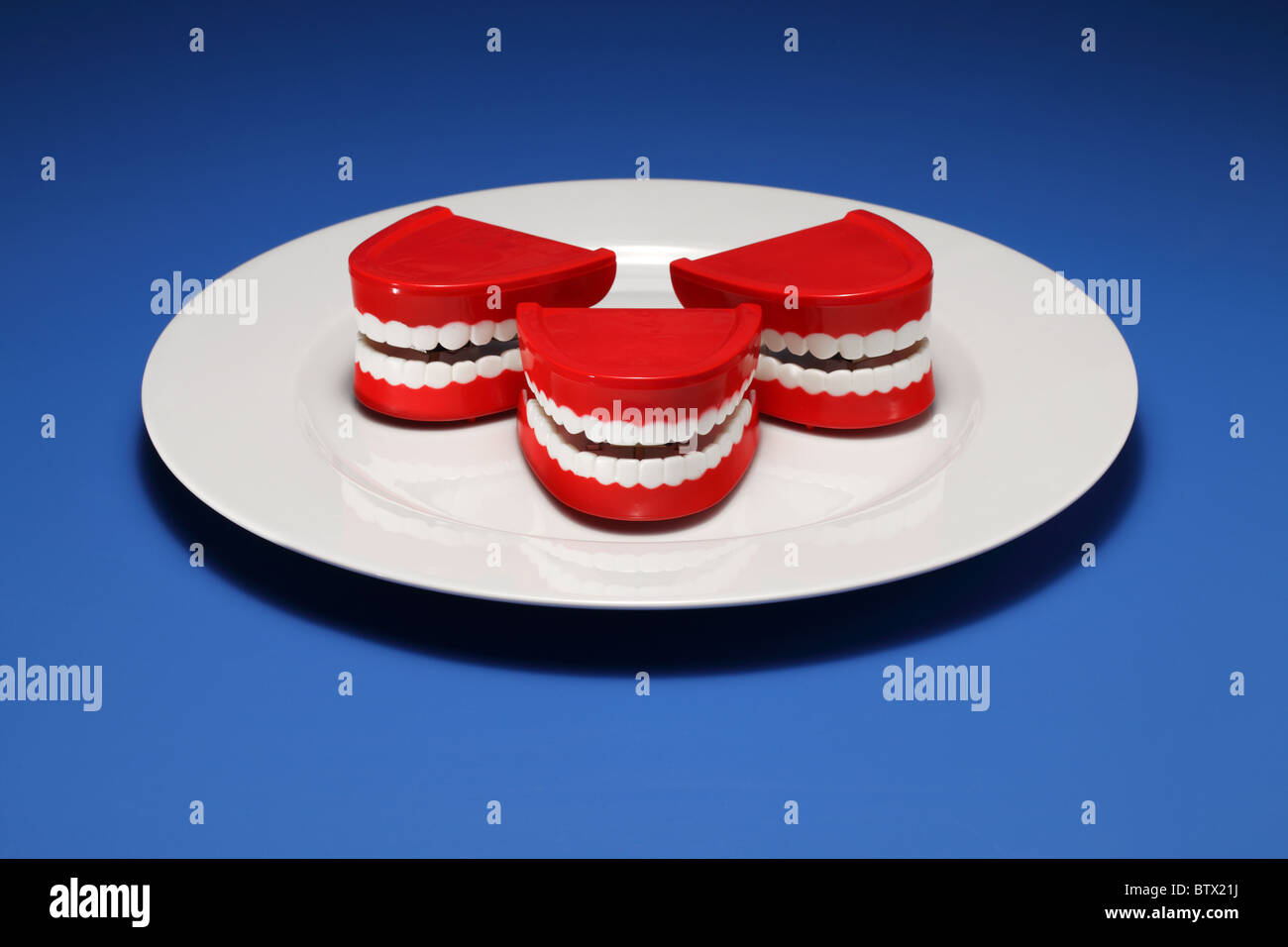 Trois dents et gencives en plastique sur une assiette blanche Banque D'Images