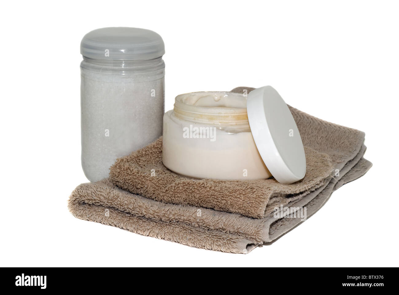 Un pot ouvert de crème visage et une bouteille de perles de bain avec une toilette sale et serviette. Banque D'Images