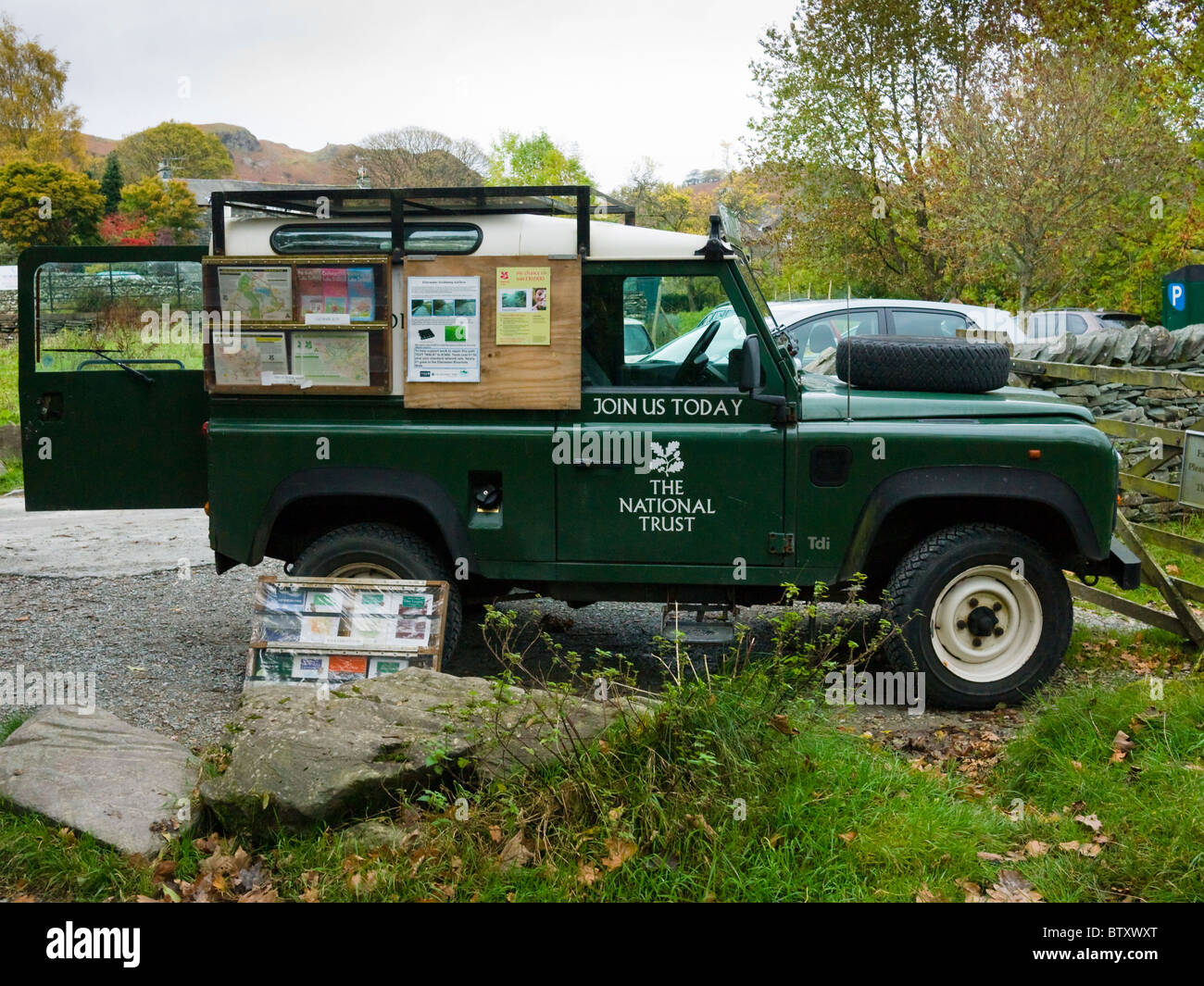 Un National Trust Land Rover Defender dans un parking à Lake Road dans le Parc National de Lake District avec un affichage pour recruter de nouveaux nouveaux membres. Banque D'Images