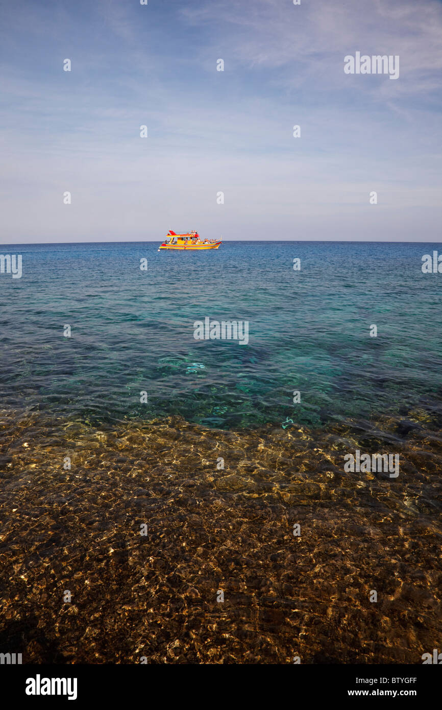 Bateau touristique jaune au large de la côte au Cap Grecko, Chypre Banque D'Images