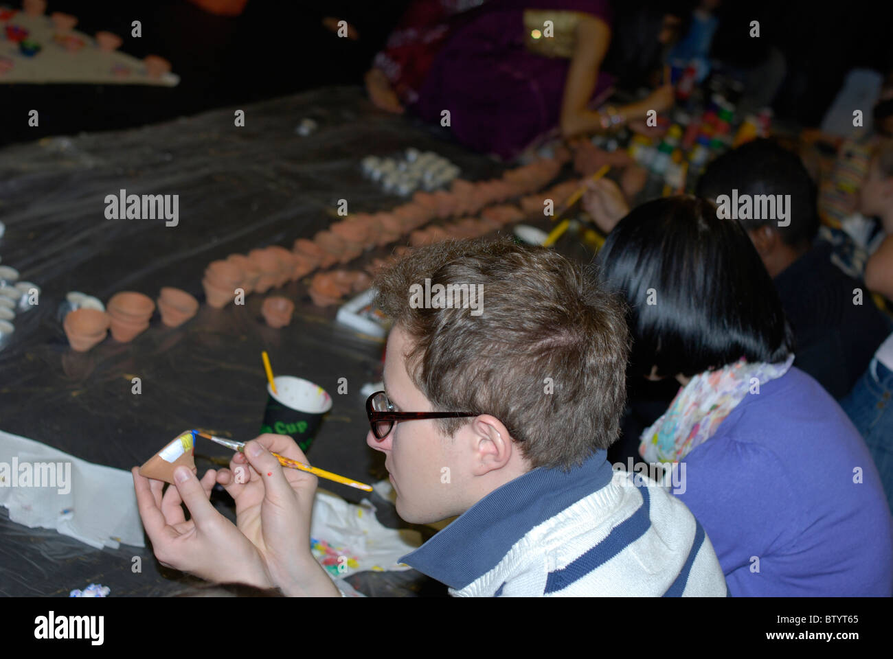 Les gens peindre de petites pots en argile pour les bougies à un festival communautaire célébrant Diwali à l'Université d'Exeter. Banque D'Images