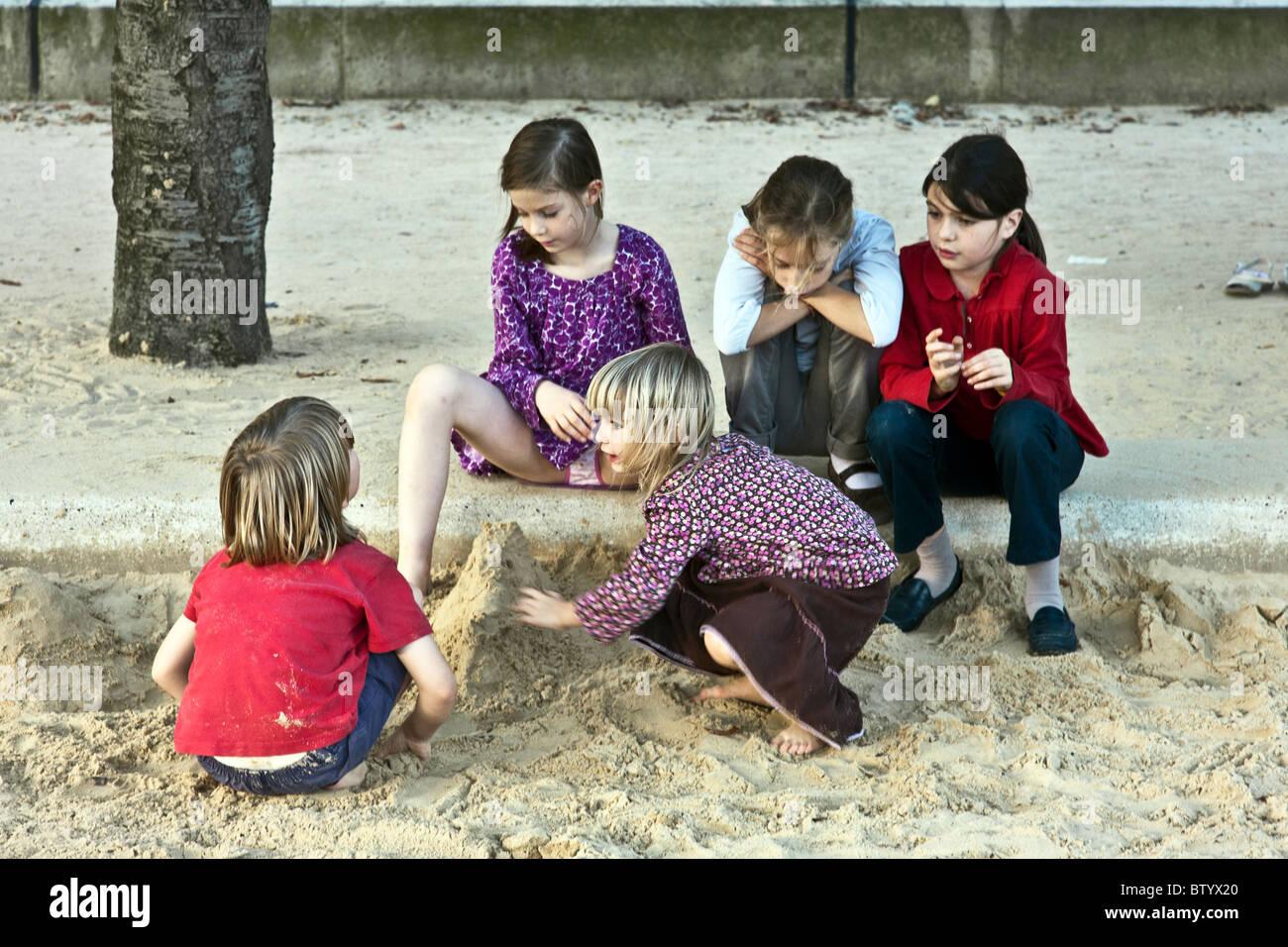 Cinq jolies petites filles françaises jouant dans sandbox dans la Cathédrale Notre Dame parc sur une belle après-midi d'automne à Paris Banque D'Images