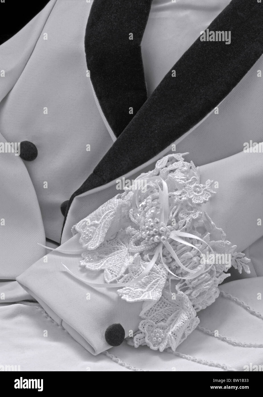 Veste de mariage classique noire et blanche avec manche reposant sur les  gants de femme et la jarretière de la mariée glissée sur la manche de  support de l'anneau froid ou du