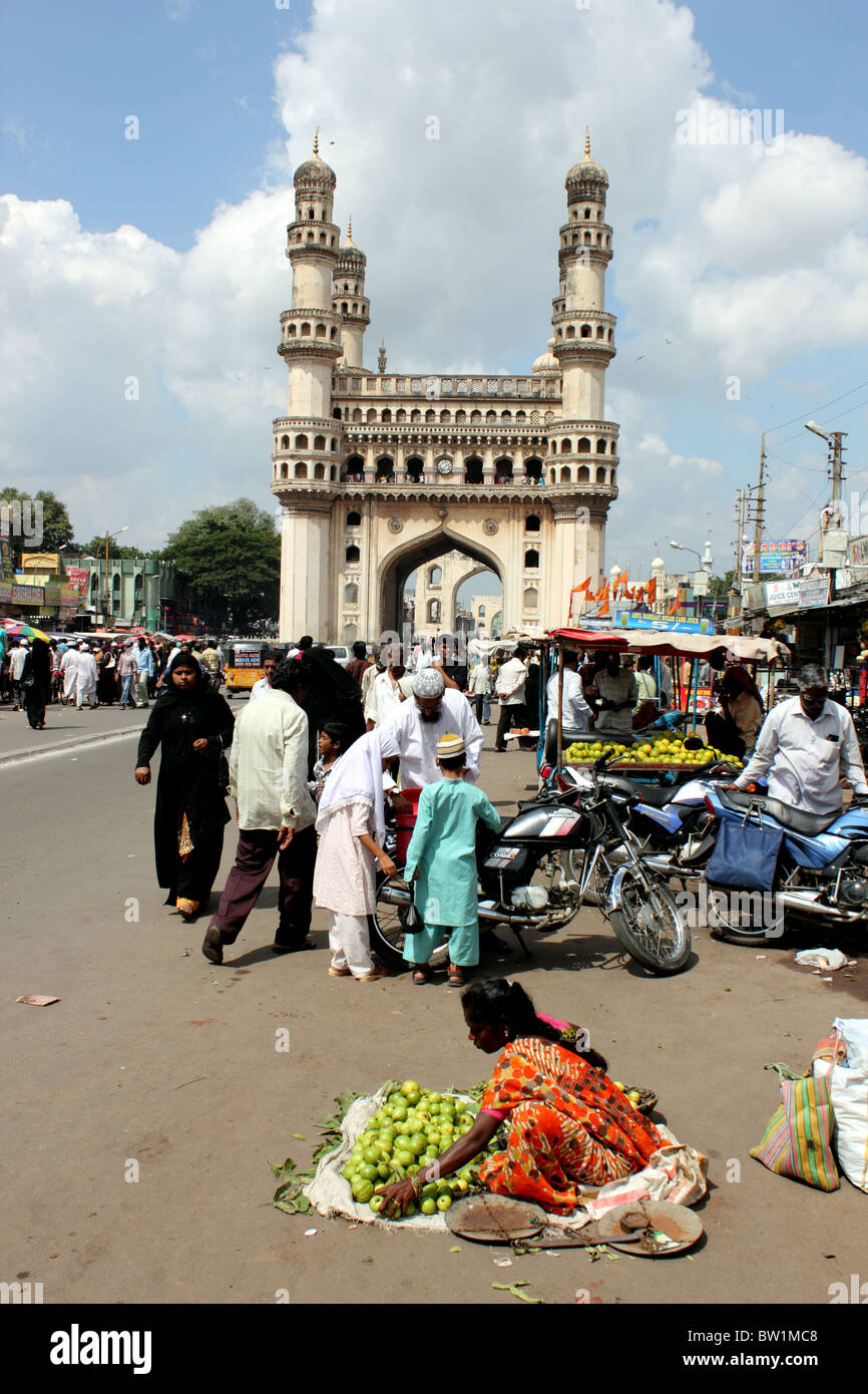 Scène de rue animée avec des personnes vendant des légumes et avec le Charminar en arrière-plan ; Hyderabad Inde Banque D'Images