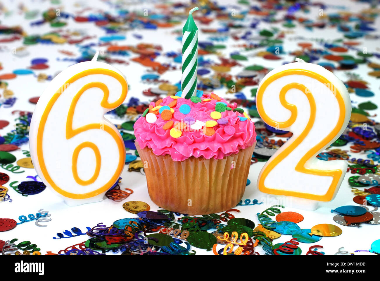 Nombre 62 cupcake célébration avec bougie et paillettes. Confettis en arrière-plan. Banque D'Images