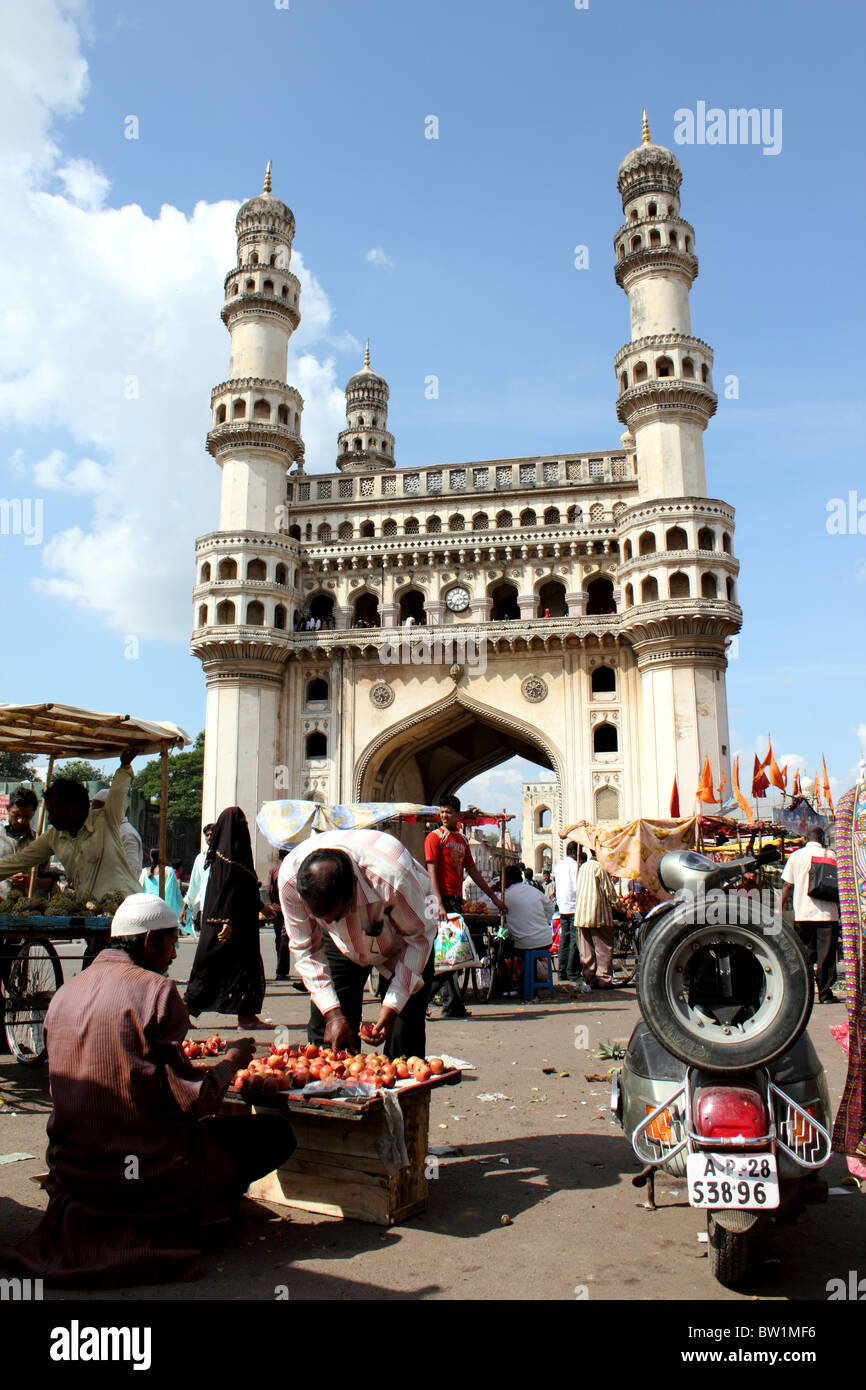 Scène de rue animée avec des personnes vendant des légumes et avec le Charminar en arrière-plan ; Hyderabad Inde Banque D'Images