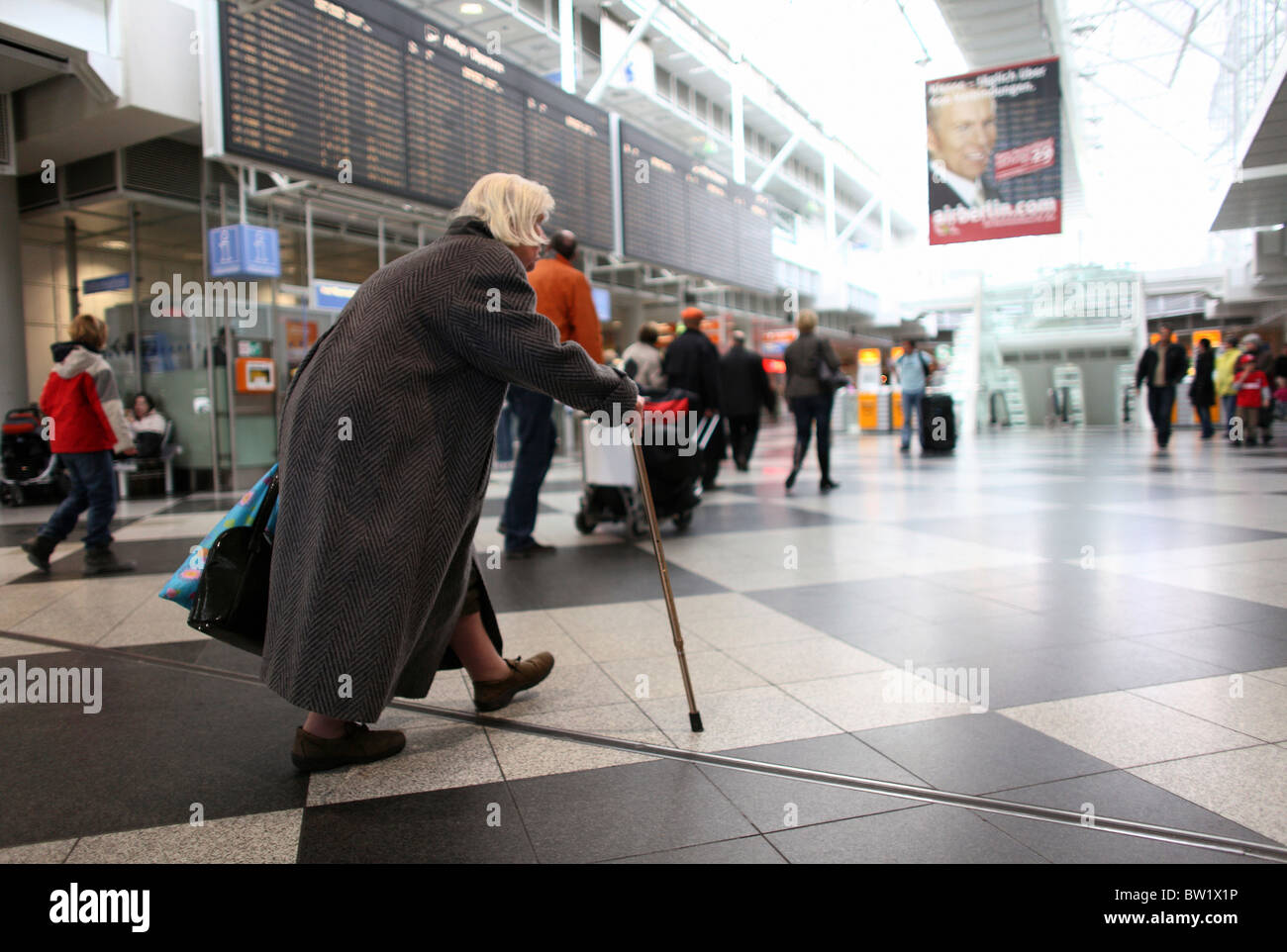 Une vieille femme marche dans le terminal de l'aéroport Franz Josef Strauss, Munich, Allemagne Banque D'Images