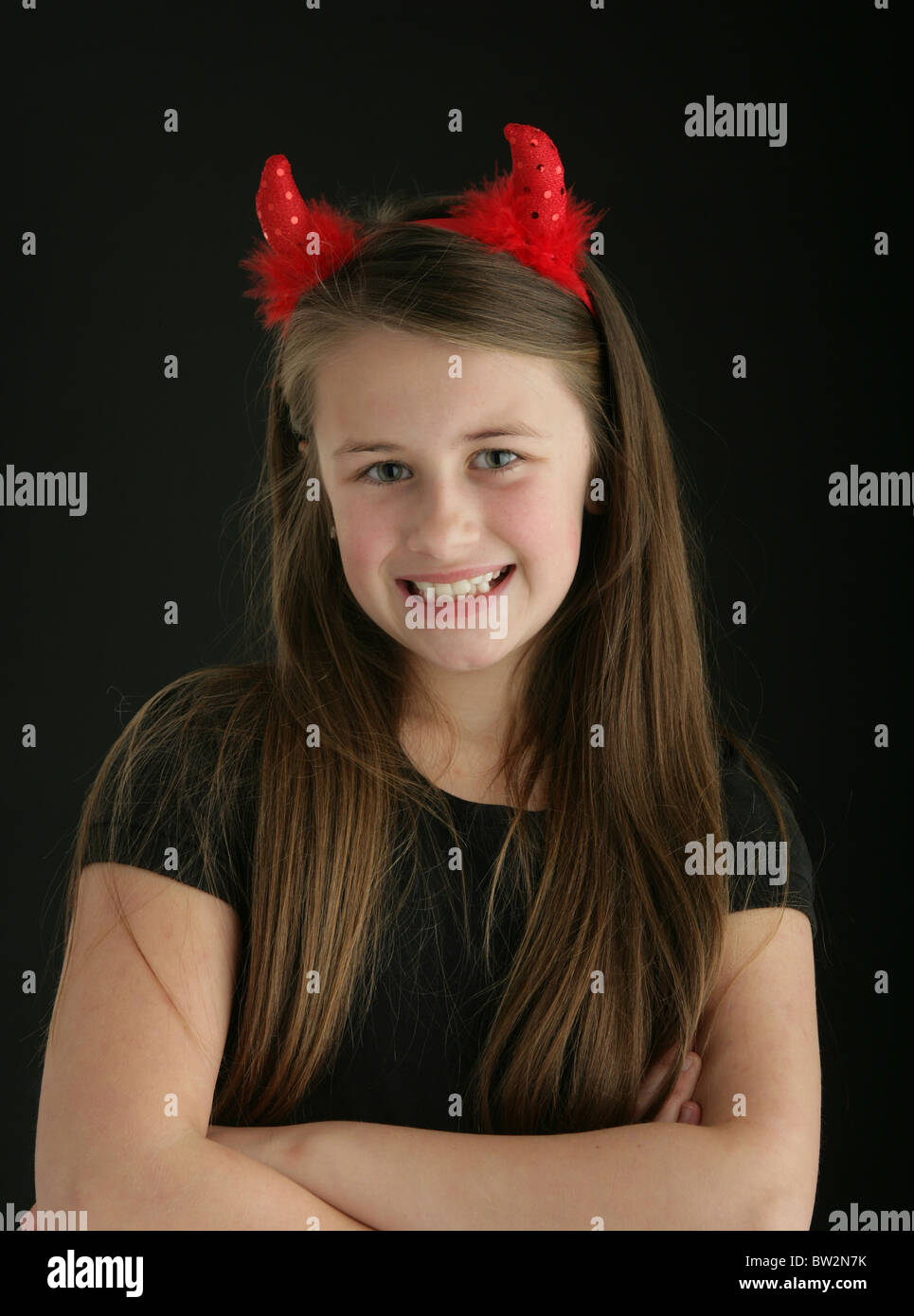 Jolie jeune fille de 10 ans portant une paire de cornes de diable rouge. Banque D'Images