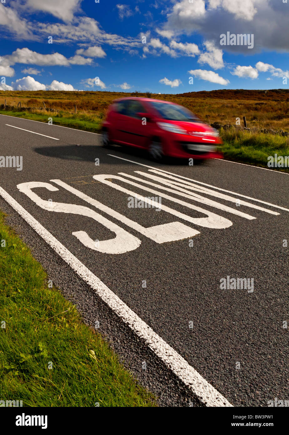 Déménagement rapide voiture près de ralentir sign painted on country road au Royaume-Uni pour avertir les automobilistes de ralentir Banque D'Images