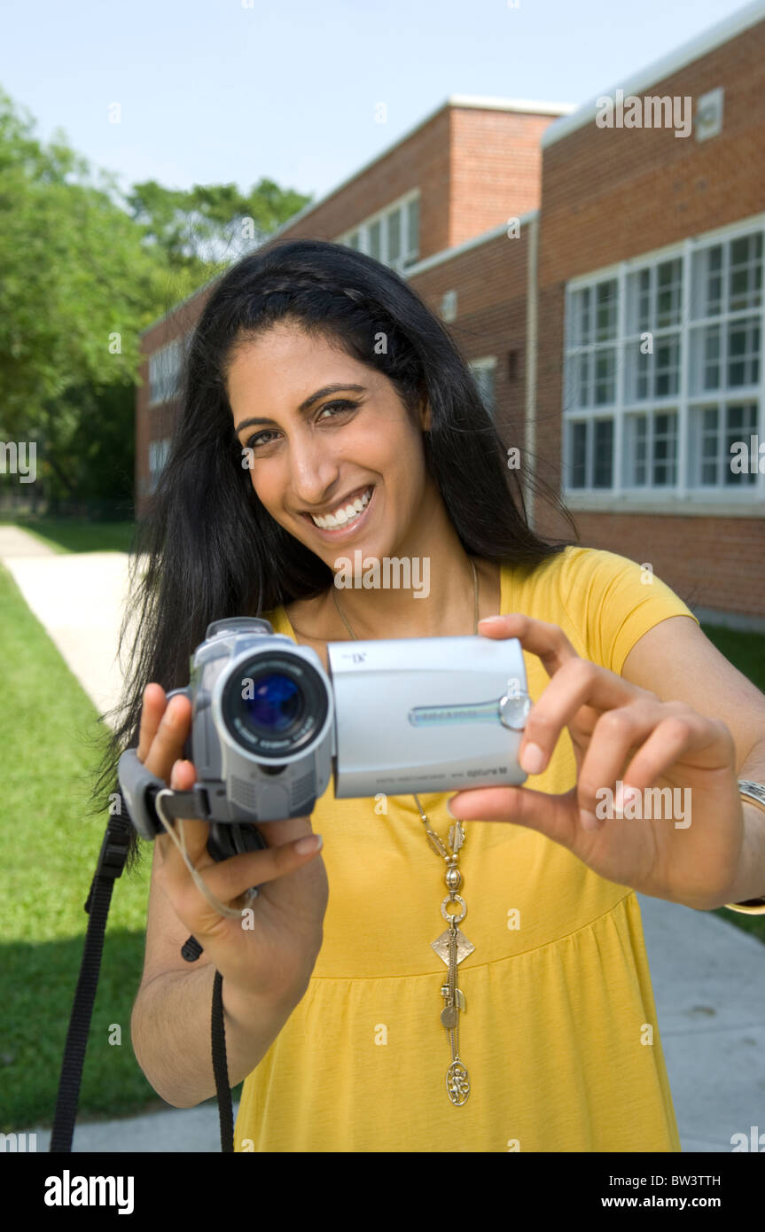 Jeune femme avec caméra vidéo, caméscope, à l'extérieur de l'école à Winnipeg, Manitoba, Canada. Banque D'Images