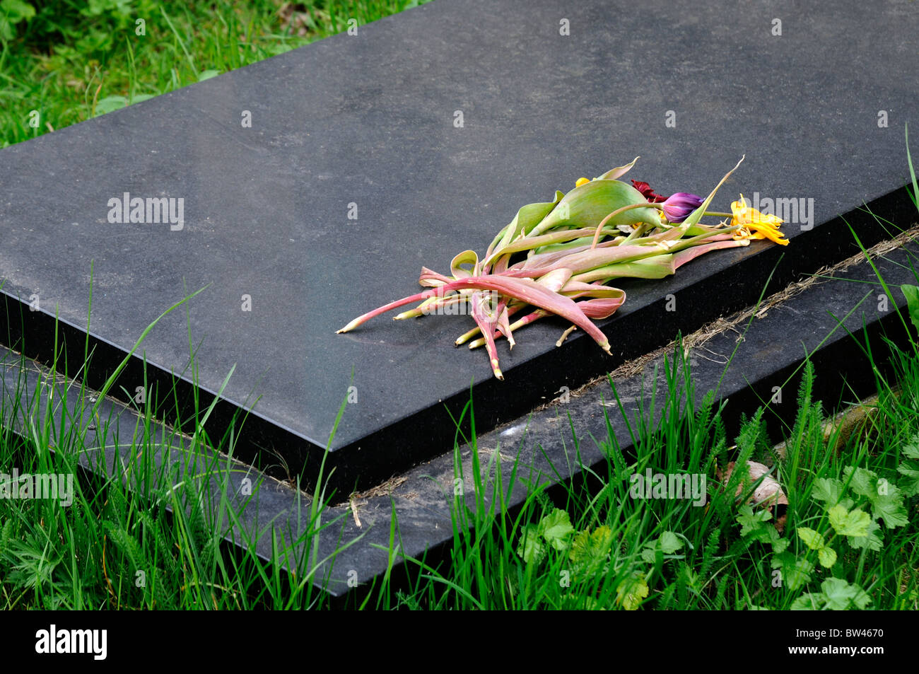 Un bouquet de fleurs fanées et mortes sur tombstone pierre sombre Banque D'Images