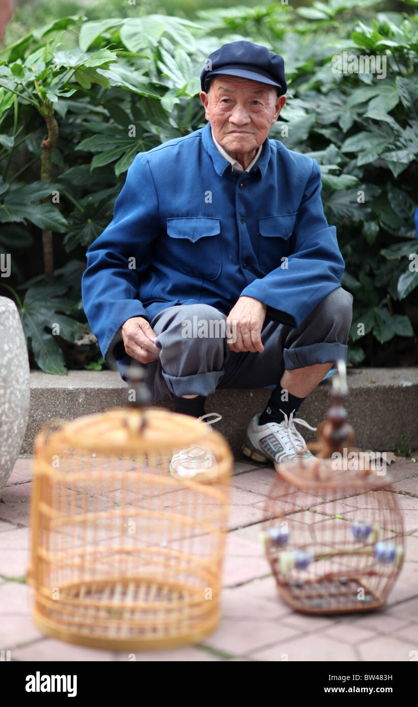 Un homme vend de petits oiseaux pour animaux domestiques, également considéré comme de la chance, dans les rues de Kunming, Chine. Banque D'Images