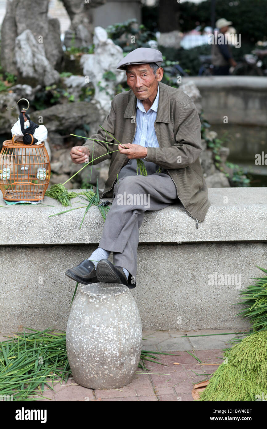 Un homme vend de petits oiseaux pour animaux domestiques, également considéré comme de la chance, dans les rues de Kunming, Chine. Banque D'Images