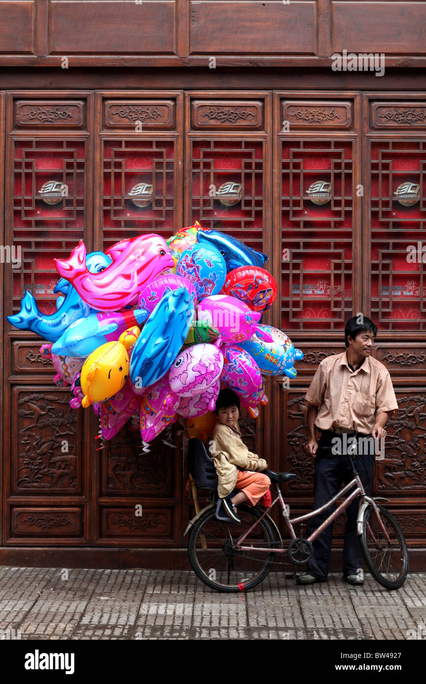 Un ballon salesman standing par portes en bois traditionnel chinois à Kunming, en Chine. Banque D'Images