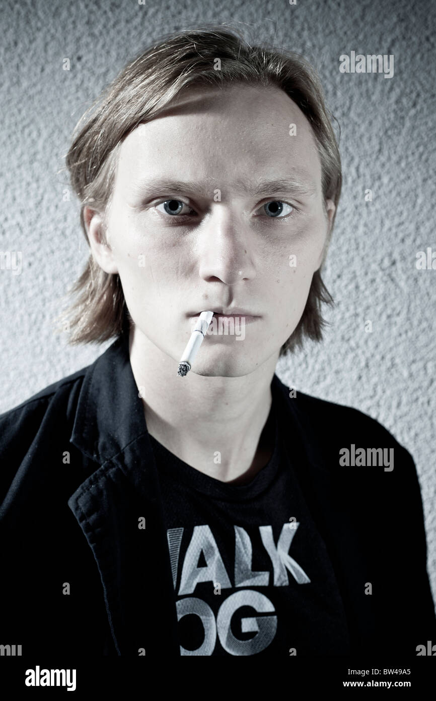 Portrait d'un jeune homme avec une cigarette contre un mur texturé Banque D'Images