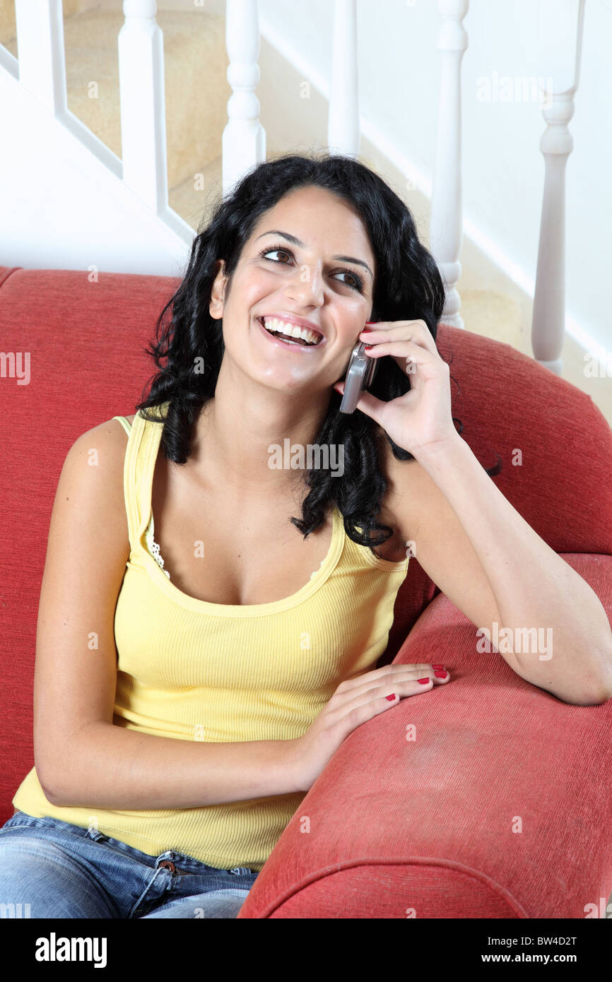 Jeune femme séduisante à la maison parler joyeusement sur son téléphone Banque D'Images