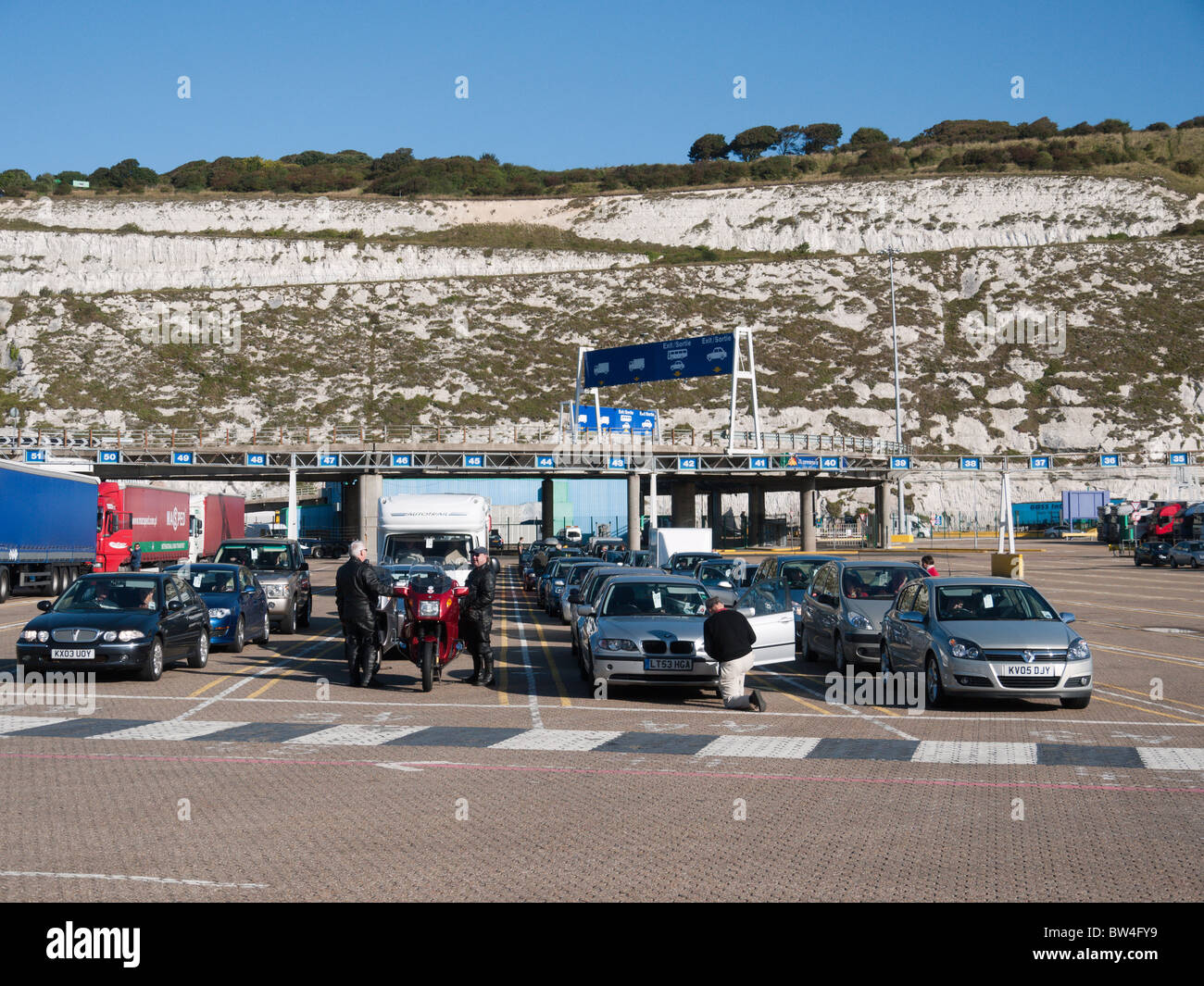 Des voitures font la queue à bord dans le port de ferries de Douvres comme camions arrivant quitte le docks Banque D'Images