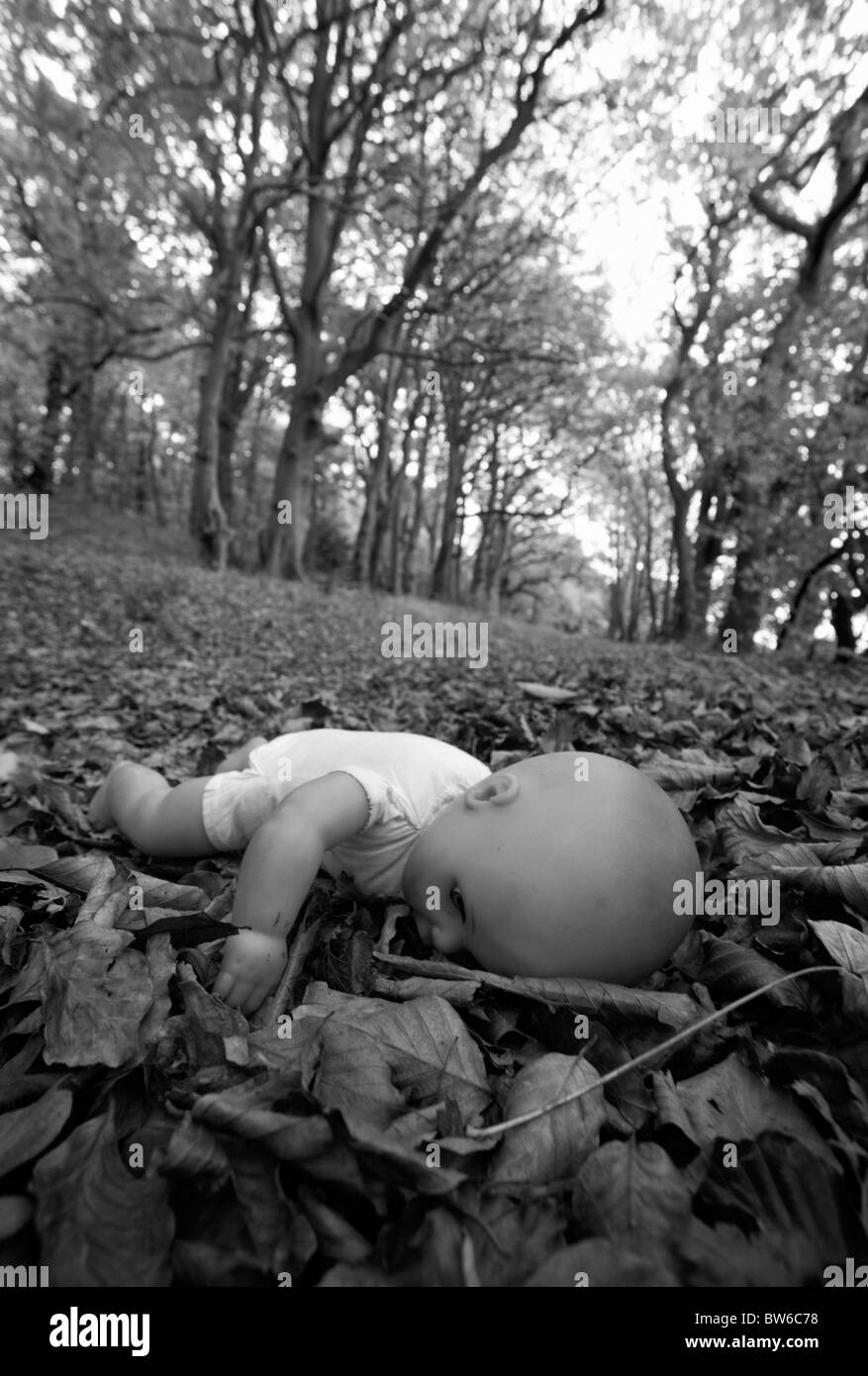 Une poupée d'enfant face vers le bas sur les feuilles tombées dans les bois. Banque D'Images