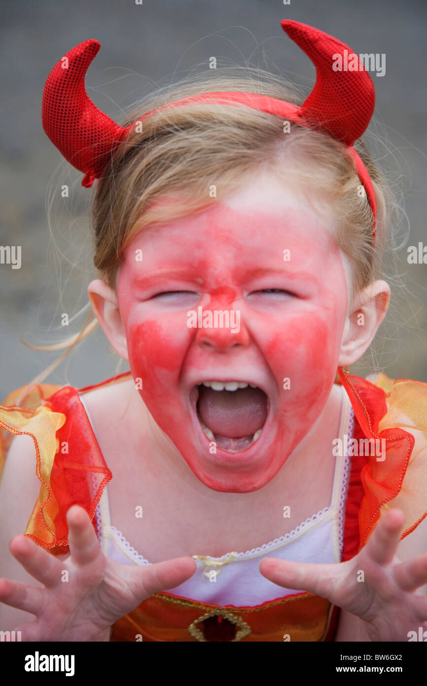 Jeune enfant (fille) portant peu d'Halloween Costume avec des cornes et la peinture pour le visage Banque D'Images