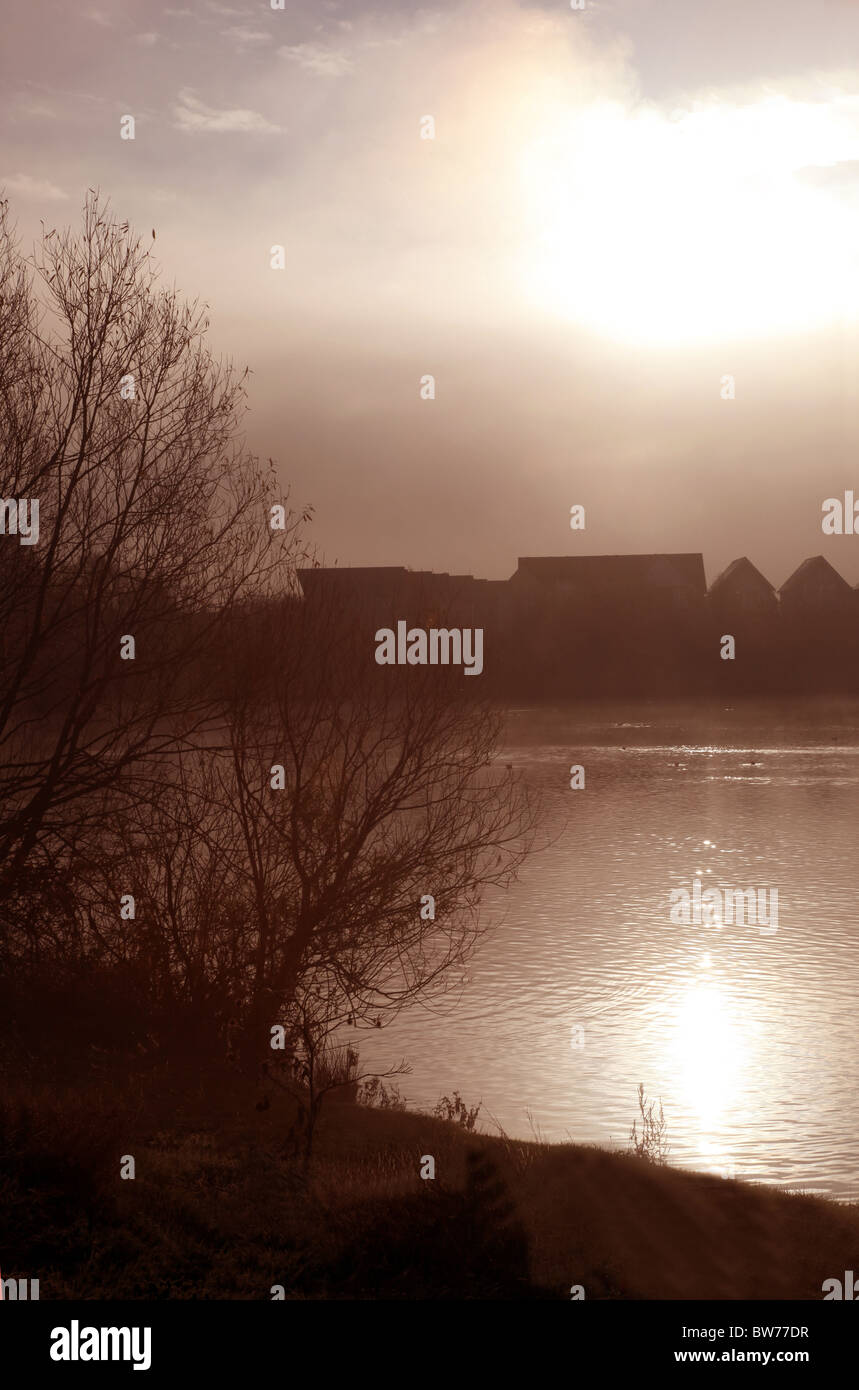 Aperçu des maisons dans la distance à côté d'un lac brumeux Banque D'Images