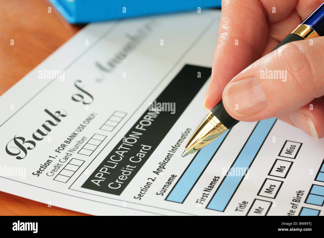 La main avec la signature d'un stylo d'une demande de carte de crédit fictif Banque D'Images