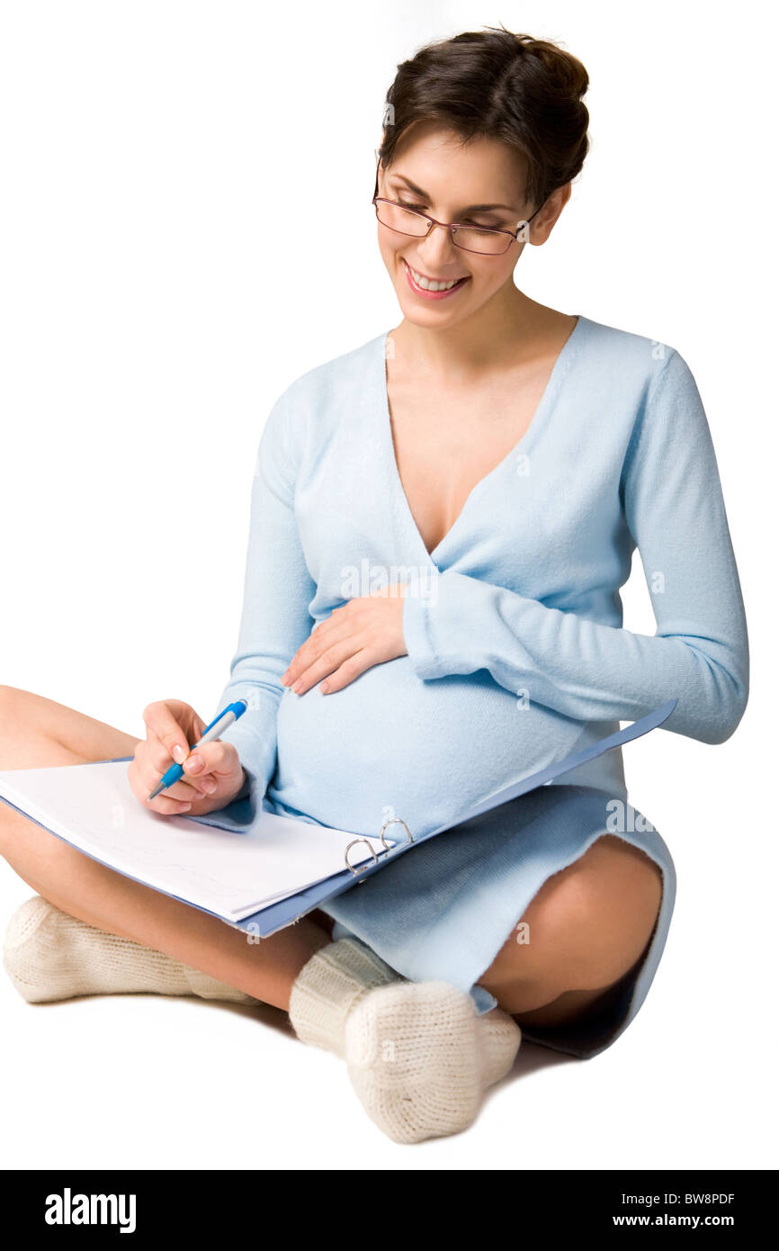 Photo de jolie femme enceinte assis en posture de lotus et en regardant ses notes Banque D'Images